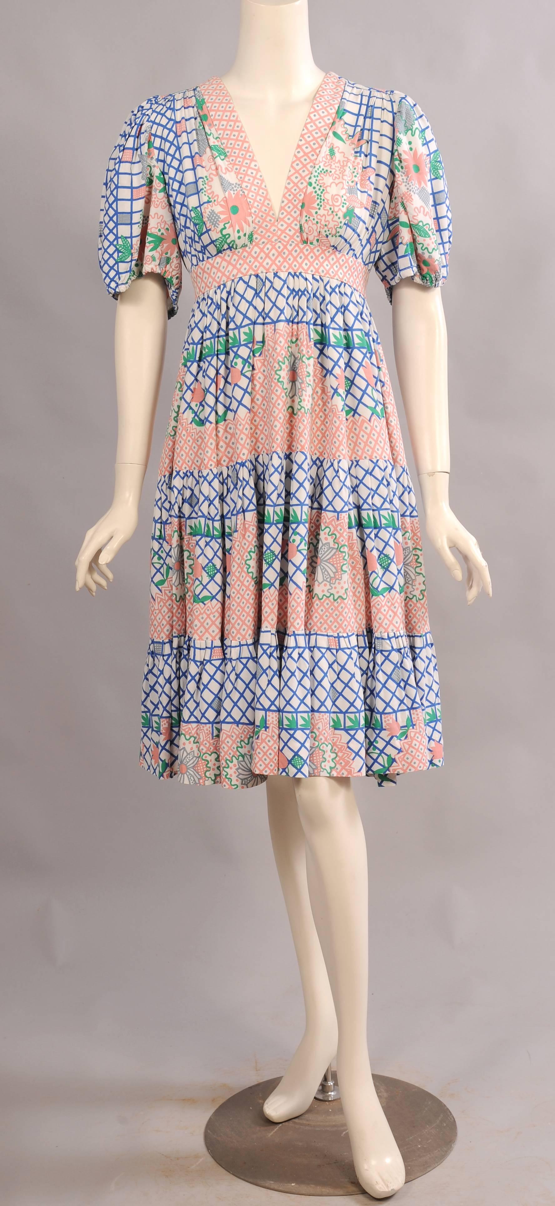 A delightful floral and geometric print designed by Celia Birtwell adds a great deal of charm to this Ossie Clark summer dress. There is a V shaped neckline above an Empire waist. The sleeves are full and gathered with elastic. The skirt has three