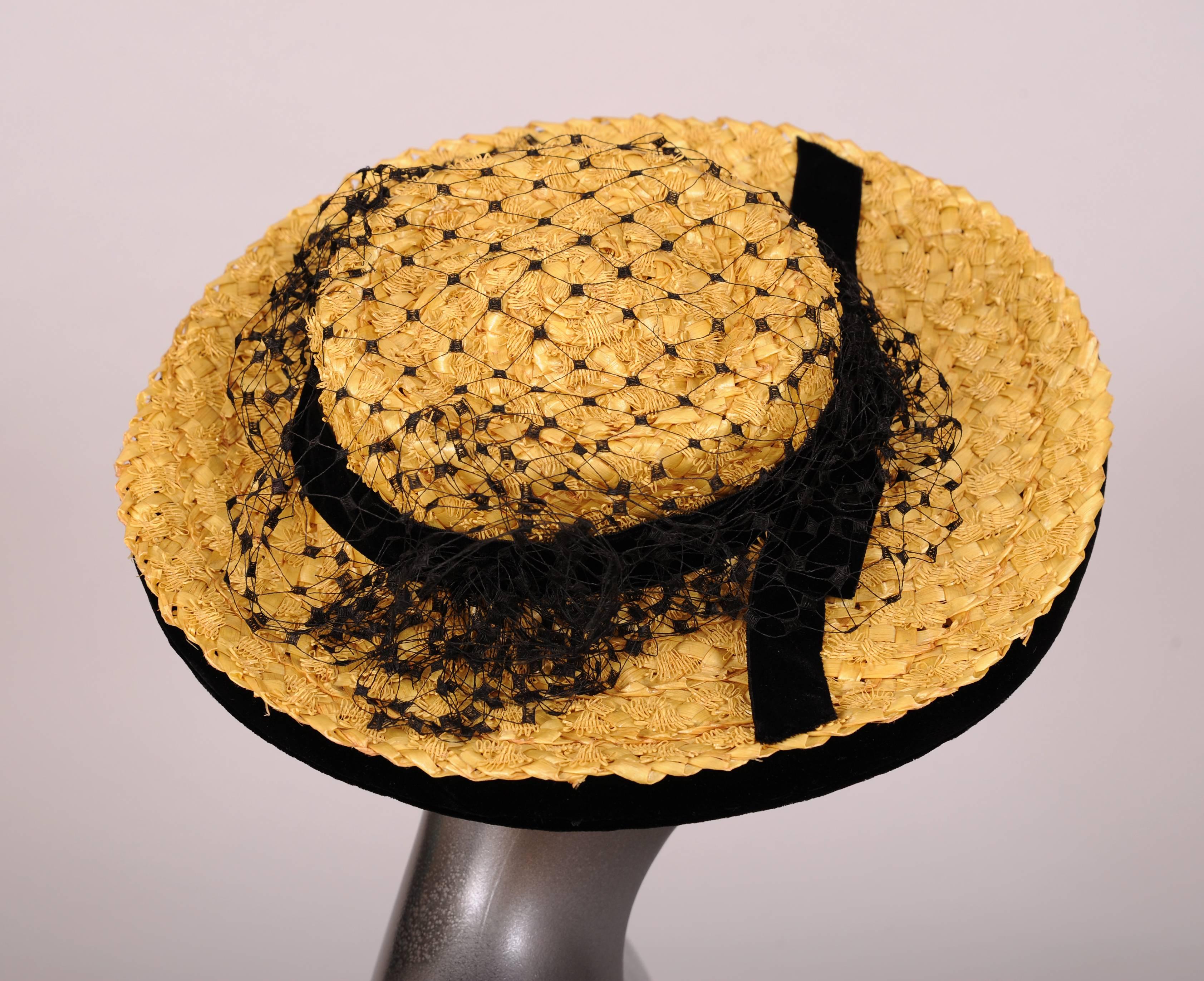 A natural straw hat with straw appliques is further embellished with a black velvet ribbon and bow at the front and a black point d'esprit veil. The under side of the brim is covered with black velvet. This milliner was located on the same street as