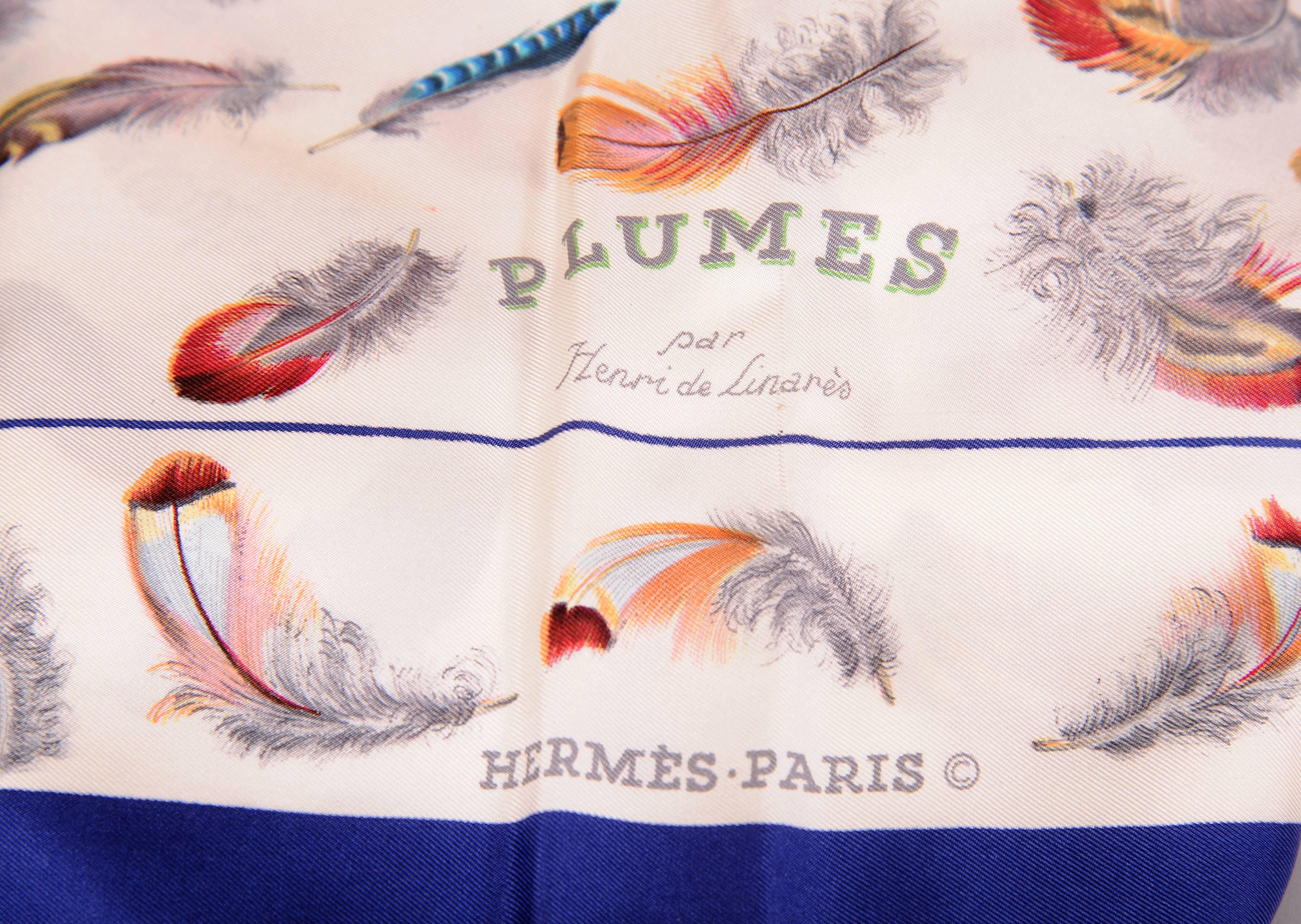 Colorful feathers float on a white silk background on this scarf designed by Henri de Linares. There is a narrow navy border, a border of similar feathers and then a wide navy outer border. The scarf is in excellent condition and it comes with the