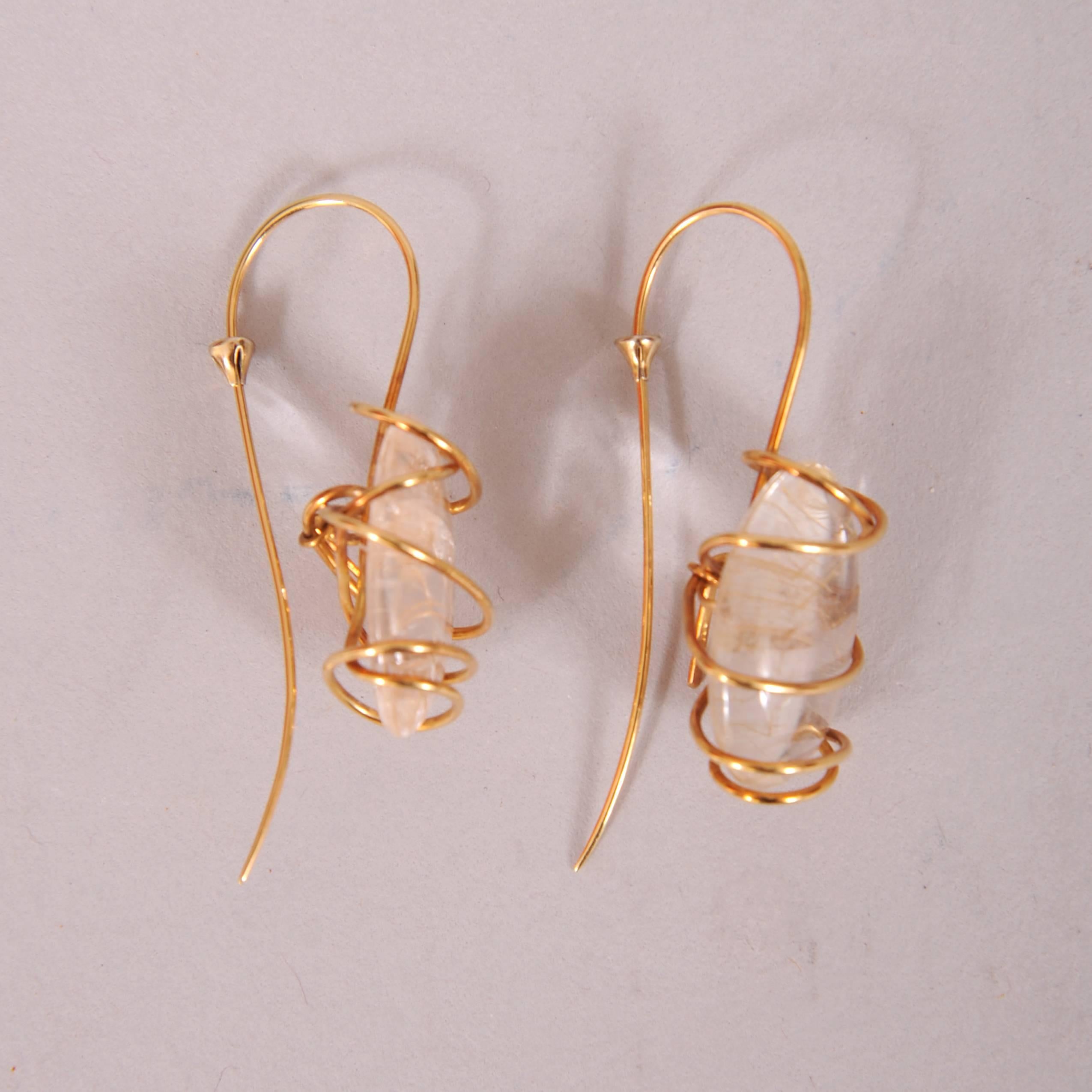 Gold bands are wrapped and twisted around these rutilated quartz stones creating a play on the gold streaks seen in the quartz. The earrings have an elegant and timeless modern look as designed by the legendary model, muse and designer Tina Chow.