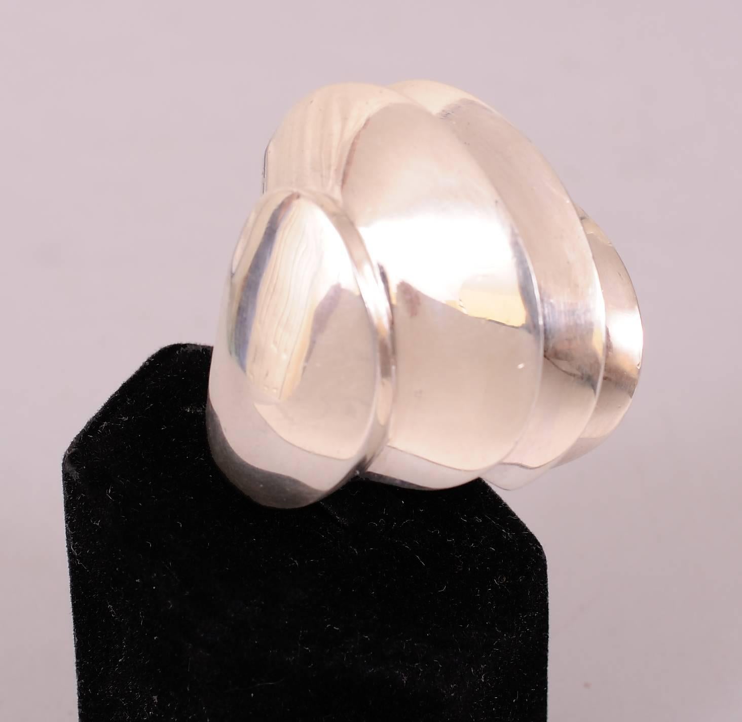 Over two ounces of sterling silver are used to make this bold architectural ring. Perfectly balanced, it is curved and angular at the same time. It is in excellent condition and measures a size 7 1/2.