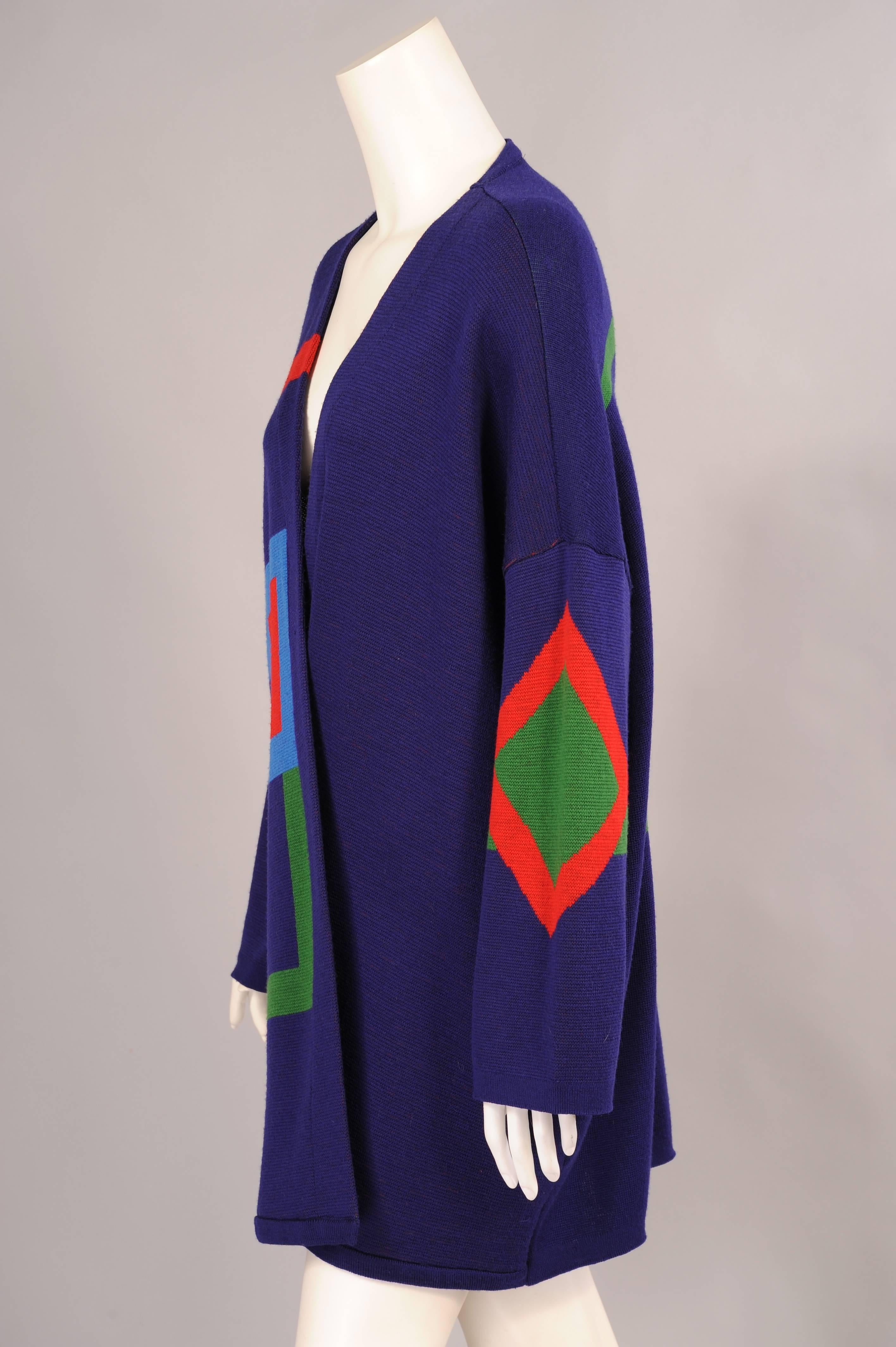 A dark purple wool sweater is enlivened with graphic geometric designs in red, green and blue. These designs are bold and colorful in the iconic style of Marimekko. This cheerful sweater is in excellent condition. One size fits
