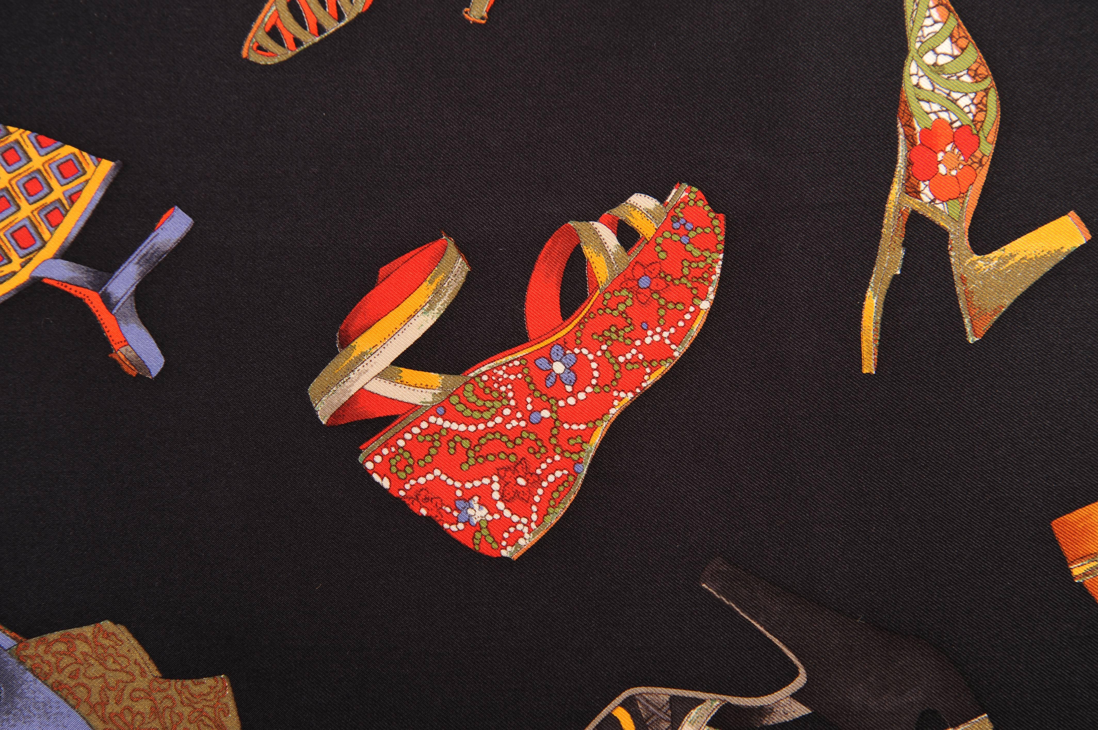 Set against a black background, images of iconic 20th century shoes from Salvatore Ferragamo are scattered across the scarf. There is a deep red woven look inner border surrounded by a wide band of gold. This band has the signature Salvatore