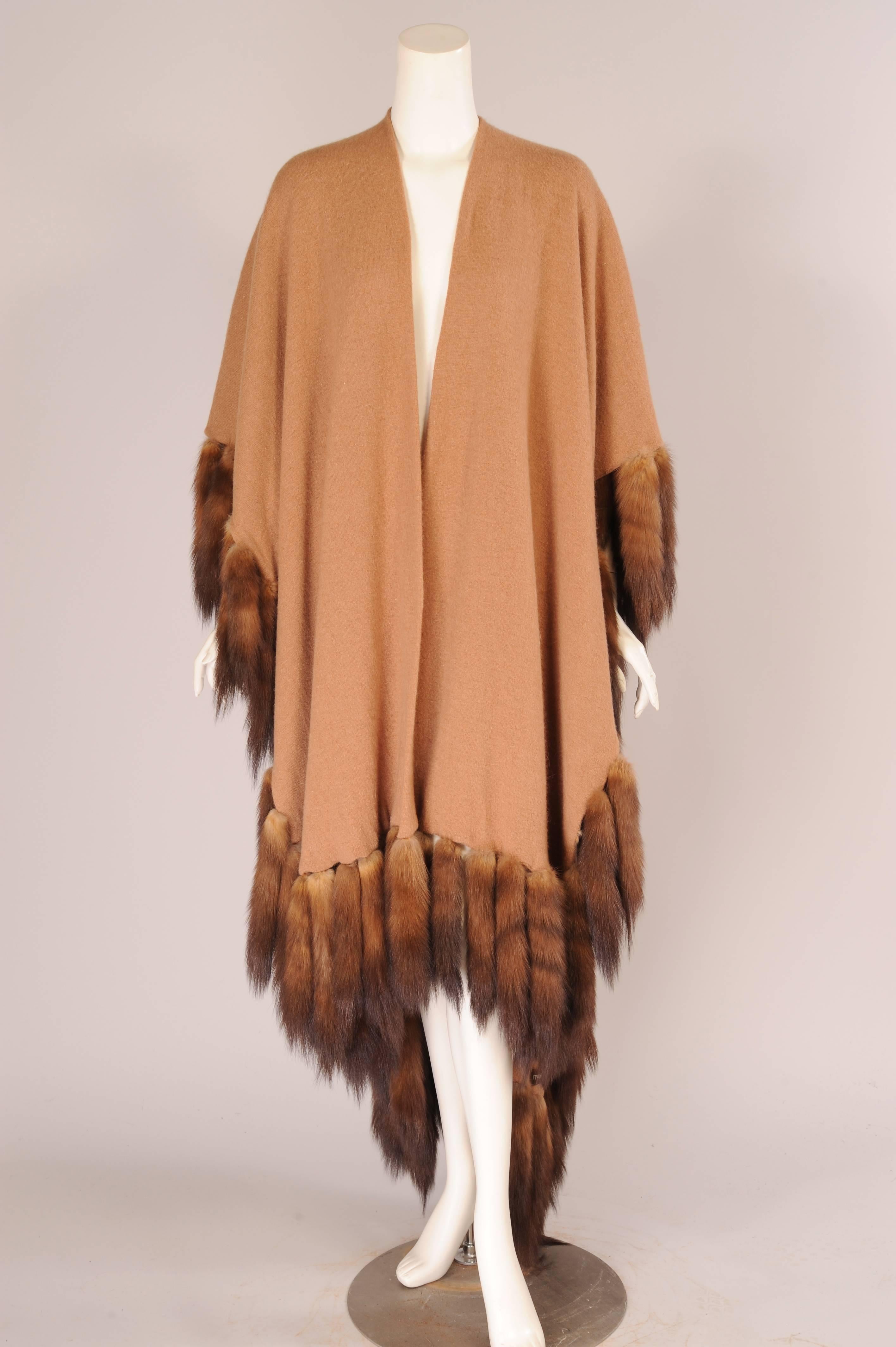 A luscious camel cashmere shawl is over sized for added length and is double thickness for extra warmth. Sable tails add a generous touch of glamour. The shawl is in excellent condition and one size fits all.
Measurements:
Length 82