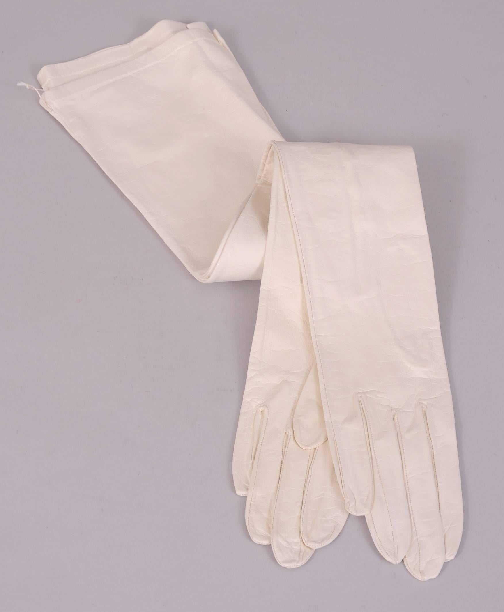 Made in France for Saks Fifth Avenue, these white kid gloves are in pristine condition. They are still sewn together as if they just left the store. There are three kid buttons at the wrist and the gloves are marked a size 6 1/2. Your glove size is