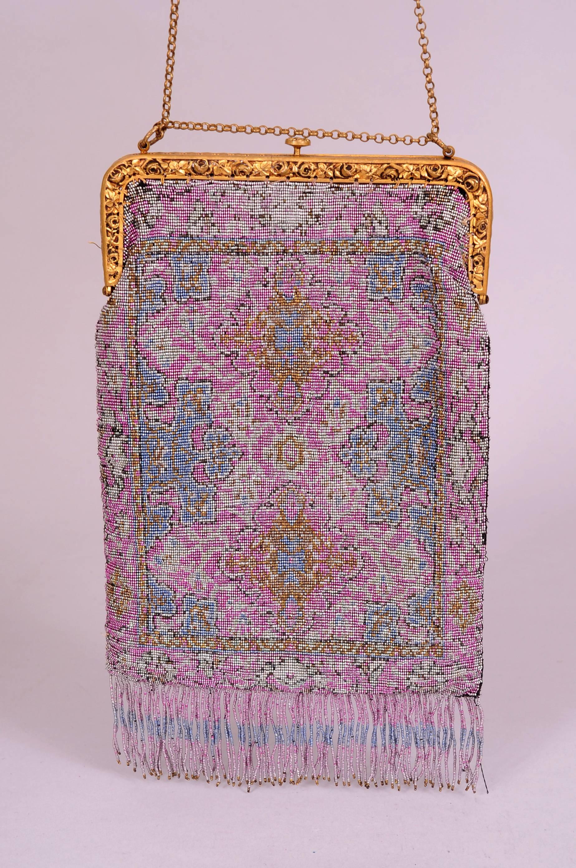 This stunning evening bag from the teens is worked in an unusual color combination using cut steel beads. Lavender, blue, silver and gold are the predominant colors in a design that is reminiscent of an Oriental carpet. The bag has a gold toned