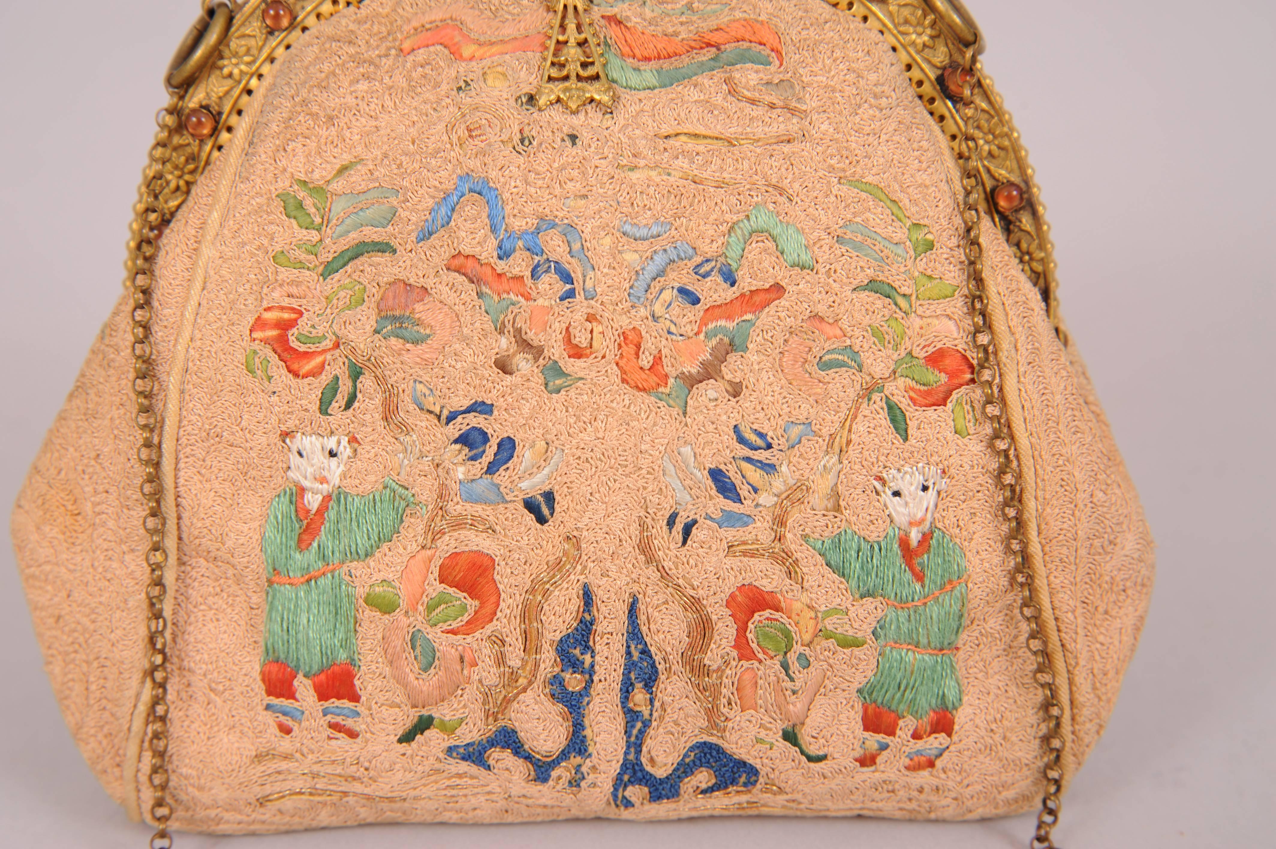 Delicate Chinese hand embroidery is worked in silk and metallic thread in shades of green, coral, peach, blue and navy and depicts two figures on the front and back of the bag. The gold toned frame is set with jewels. The silk lining is in good