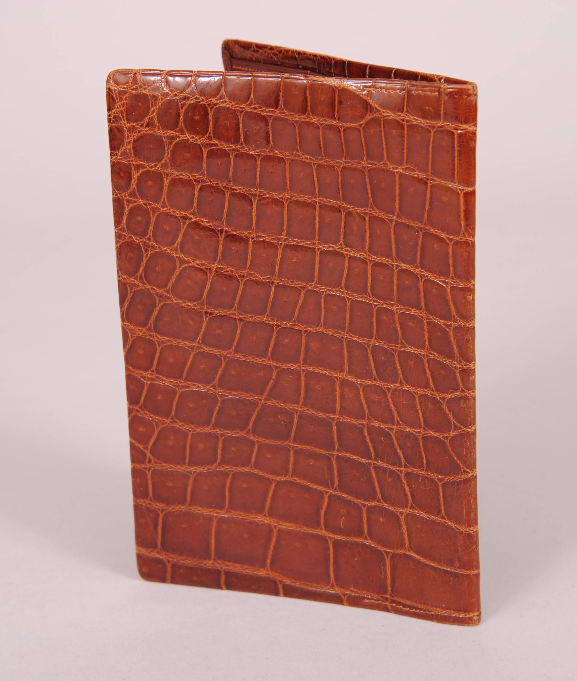 A glazed brown crocodile exterior is matched to a brown fine leather interior. There is a coin purse and two open, silk lined  compartments on one side. The other side has two large silk lined sections and two smaller silk lined sections
 for