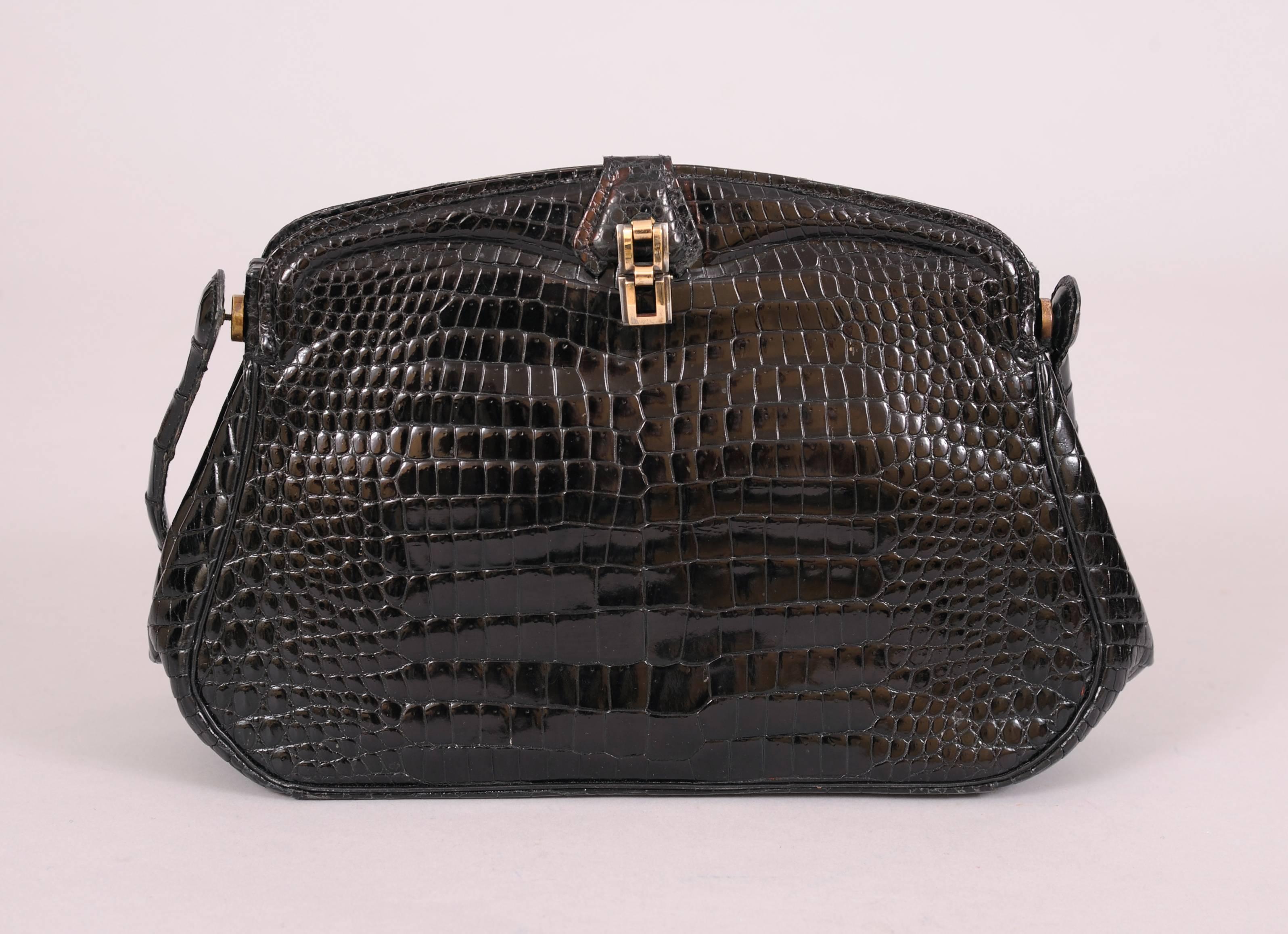 This elegant black crocodile evening bag is made from beautiful matched skins on the front and back. The handle swings down to create a clutch. There is a hallmarked sterling silver and gold clasp. The leather lined bag has two open sections and a