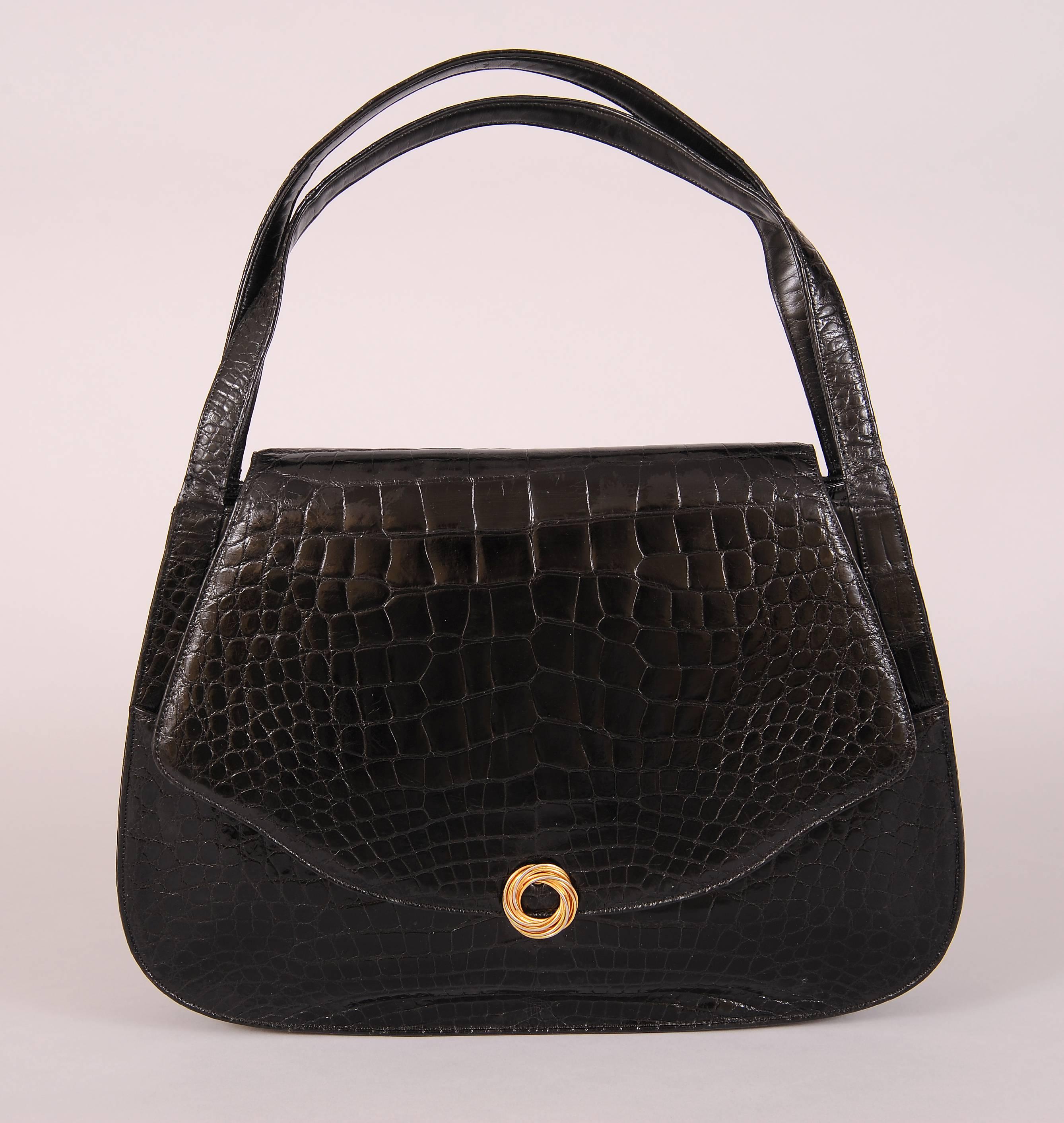 This large double handled alligator bag has a decorative gold clasp on the front and a large slip pocket on the back of the bag. There is another slip pocket on the front of the bag that is only visible when the bag is open. Inside there is a slip