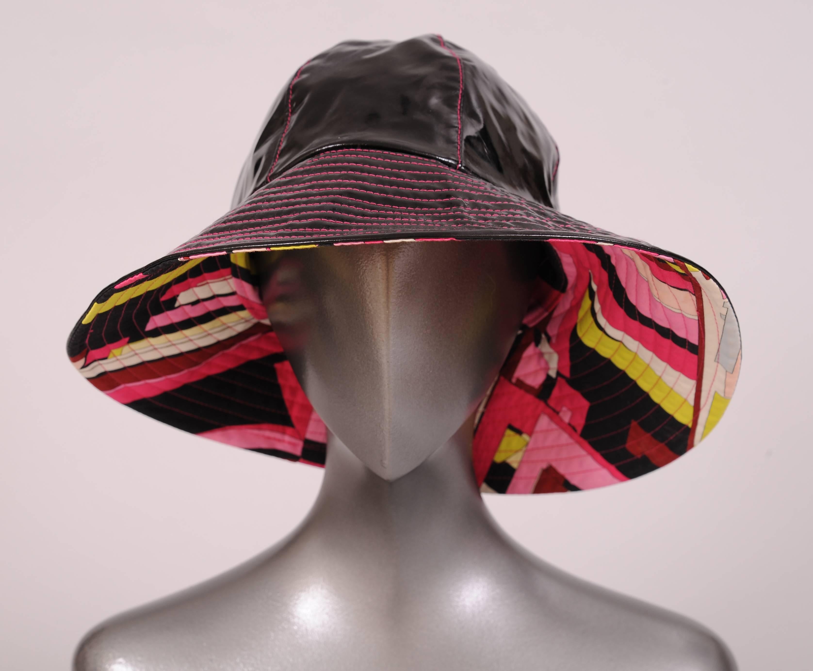 This hat will brighten the worst rainy day. A shiny black exterior is stitched with hot pink thread on the crown sections as well as the channel quilted brim. The interior is a burst of beautiful colors in a Pucci cotton print. Every shade of pink