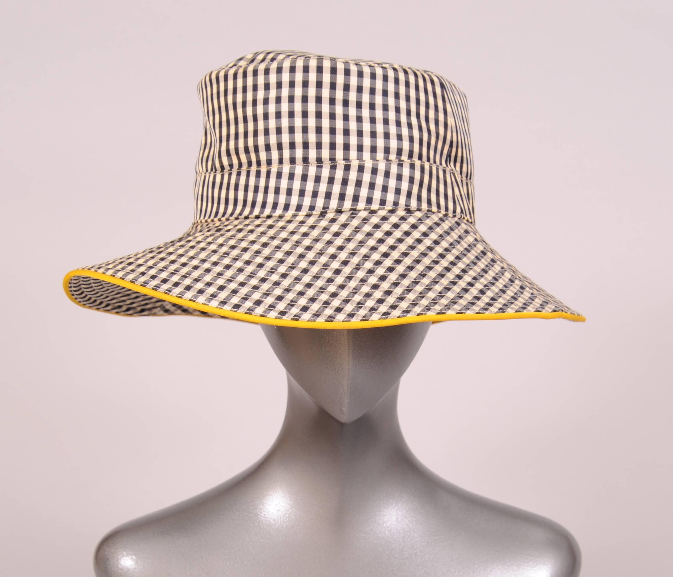 This charming black and white checked silk hat has a brim edged with daffodil yellow silk. The brim is channel quilted and the hat band has an embroidered H on the right side. This great hat is in excellent condition and marked a size