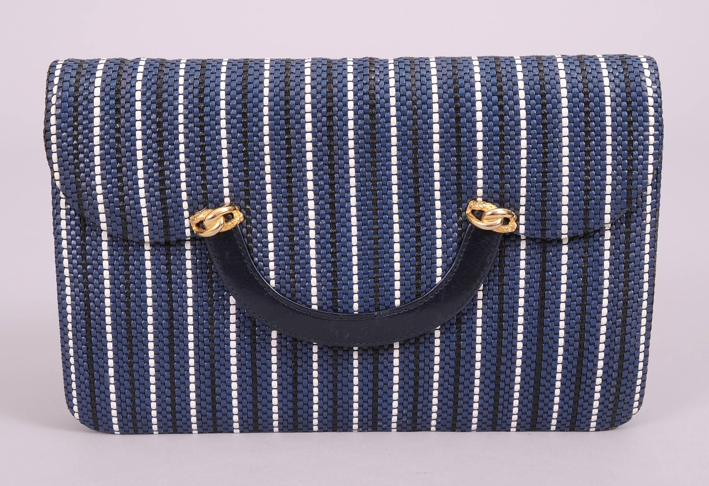 Narrow strips of navy blue, midnight blue and white leather are woven together to create a very chic bag. This bag is from the famous French jeweler Fred, located in the George V Hotel on the Place Vendome. It has a navy leather band at the center