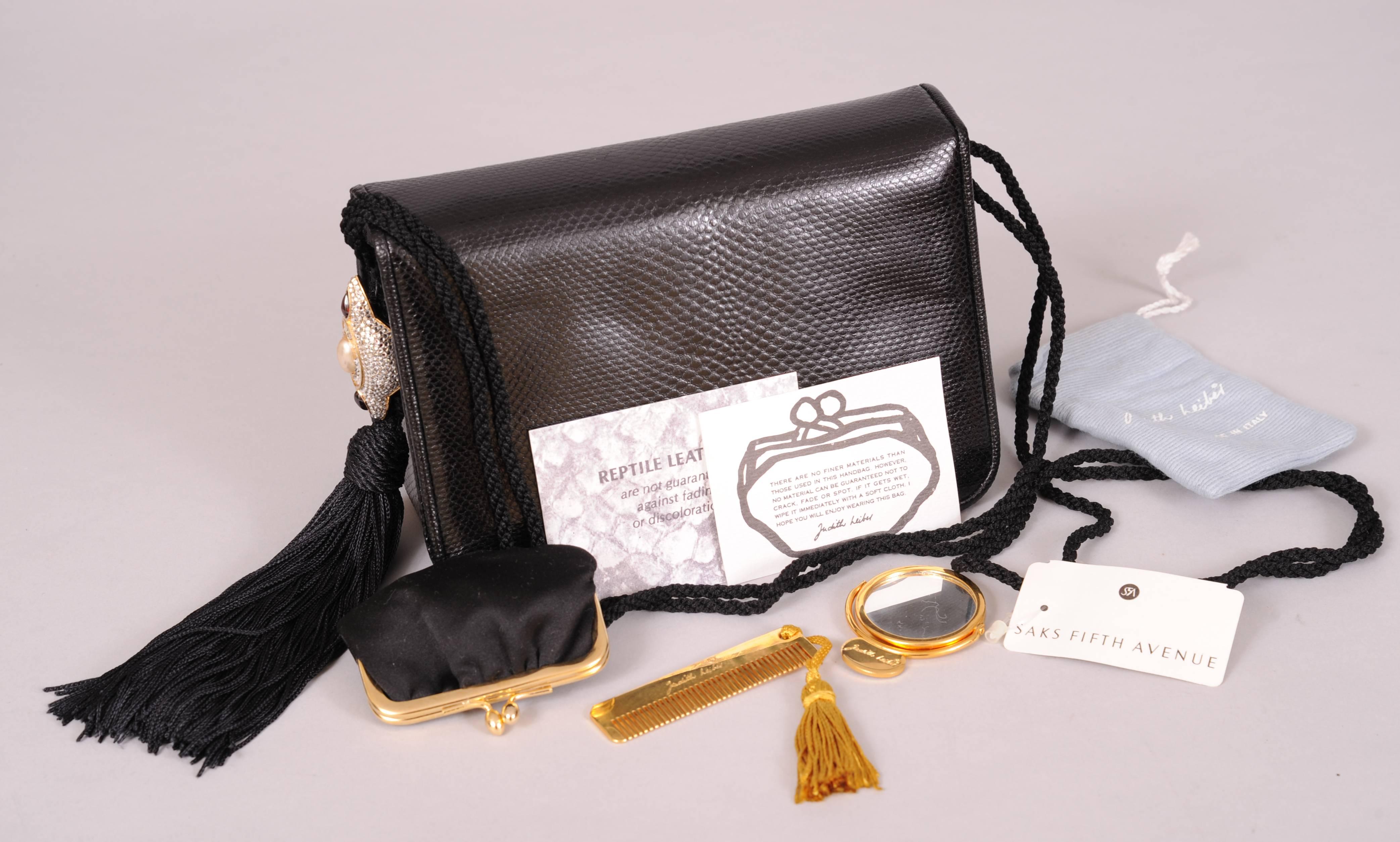 This sleek black karung bag was purchased from Saks Fifth Avenue and never used. There is a large diamante ornament with a faux pearl and rubies on each side. One side is also adorned with a black silk tassel. The bag has an optional black silk cord