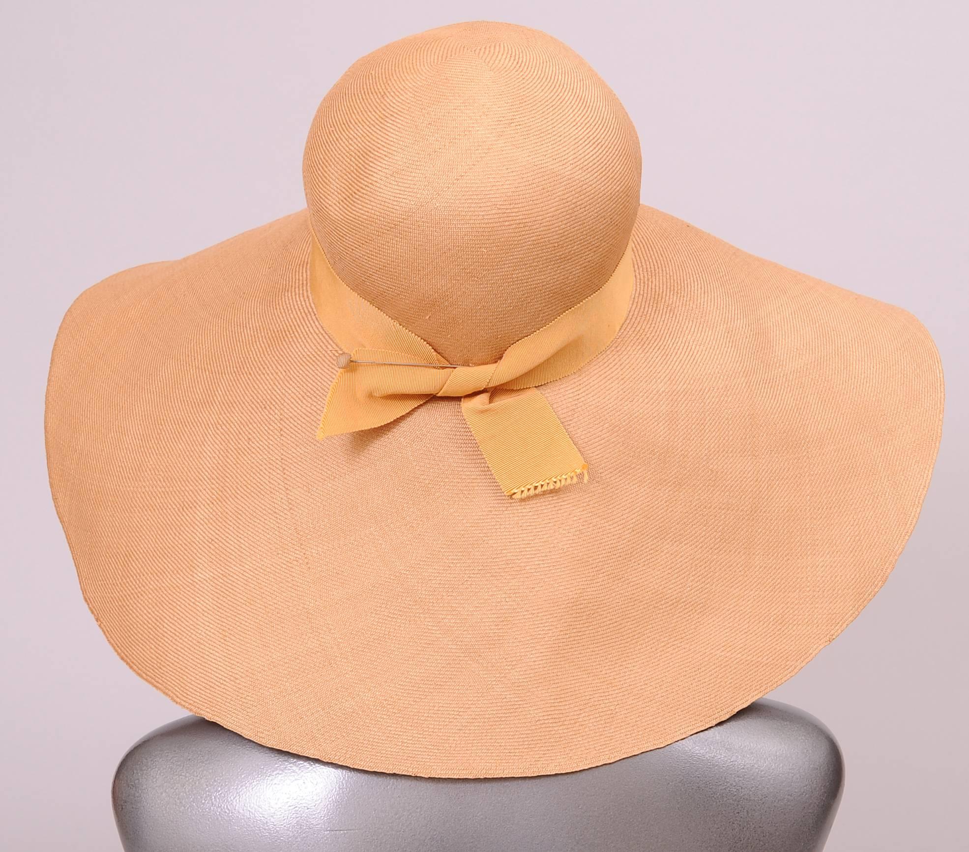 A broad floppy brim adds glamour and mystery to the wearrer of this finely woven natural straw hat designed by Adolfo. The crown is trimmed with a matching gros grain ribbon hat band. This hat is i excellent condition.
Measurements;
Interior