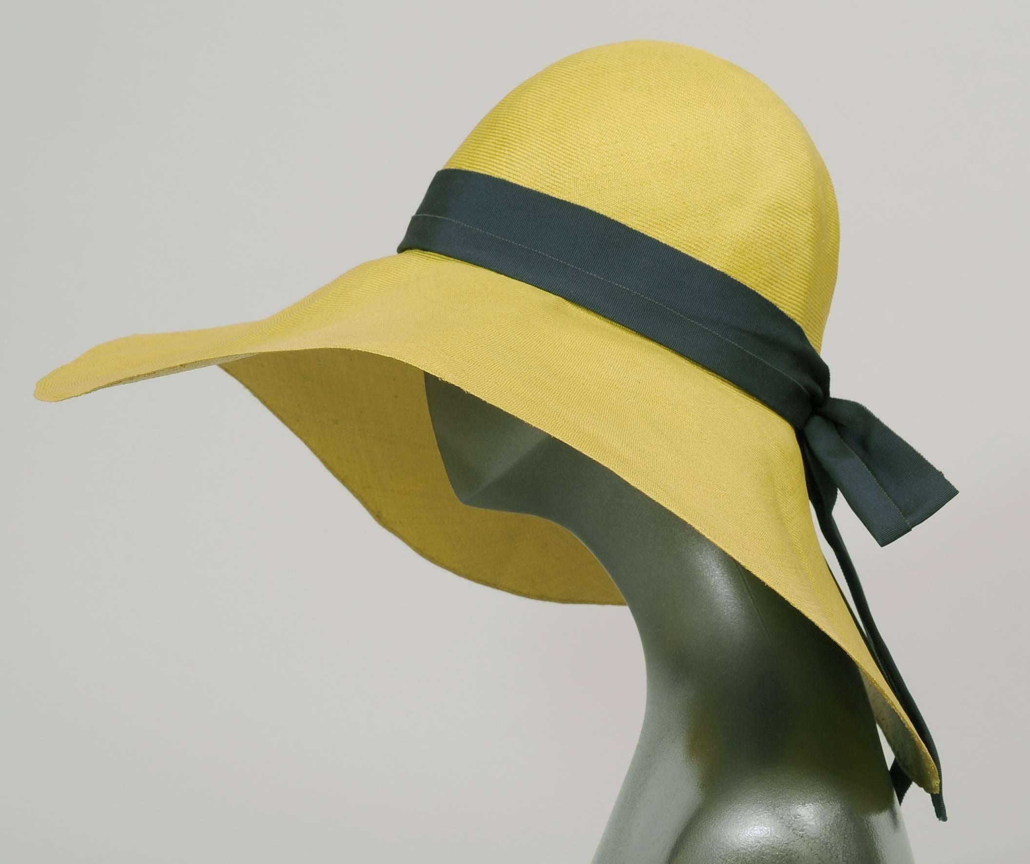 A broad floppy brim adds glamour and mystery to the wearer of this finely woven chartreuse straw hat designed by Adolfo. The crown is trimmed with a navy blue gros grain ribbon hat band. This hat is in excellent condition.
Measurements;
Interior