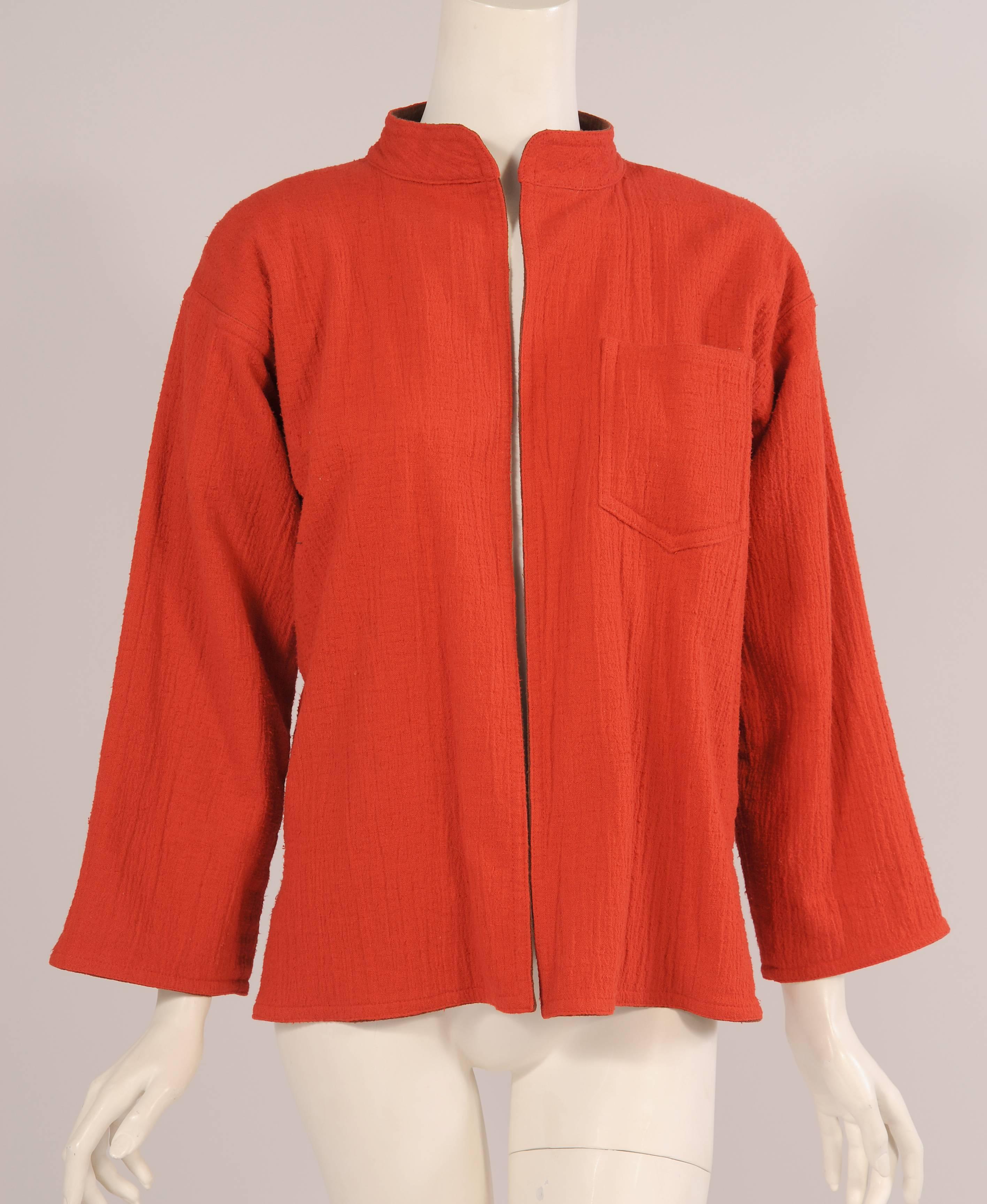 This crinkled cotton jacket is so beautifully made it could be worn inside out. It is orange on the outside and brown inside with decorative orange stitching. The jacket is cut in a simple Japanese style with a band collar, slit sides and no