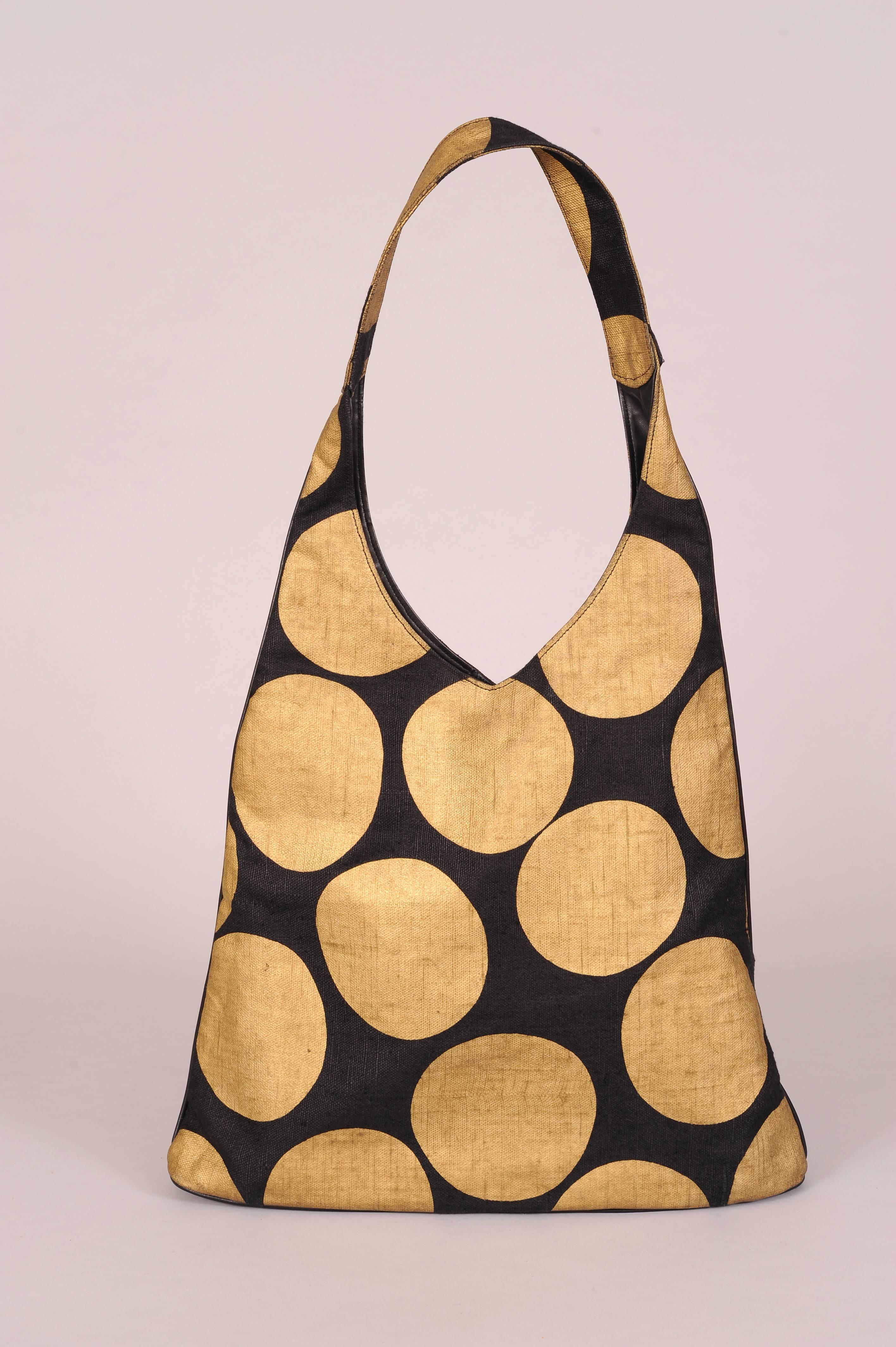 This striking black canvas bag with giant gold dots is fully lined with black leather and it has a small matching zippered bag attached by a narrow leather strap. The wide flat strap fits comfortably on your shoulder and the flat bottom sits easily.