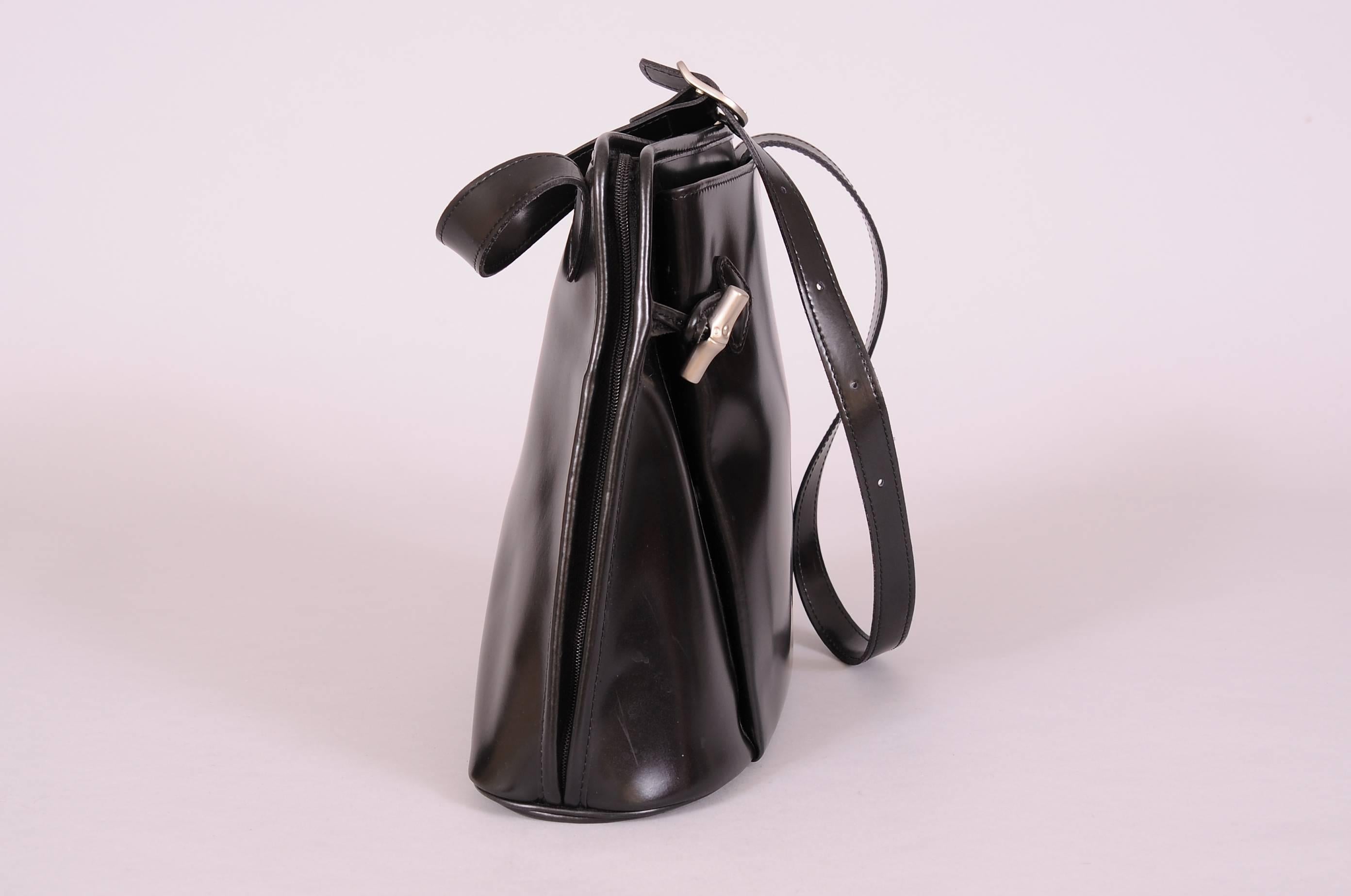 This supple black leather bag has a wide base tapering as it rises to the top of the bag. There is a zipper closure which starts on the one side of the top and unzips across the top and all the way down the other side. An interior gusset keeps