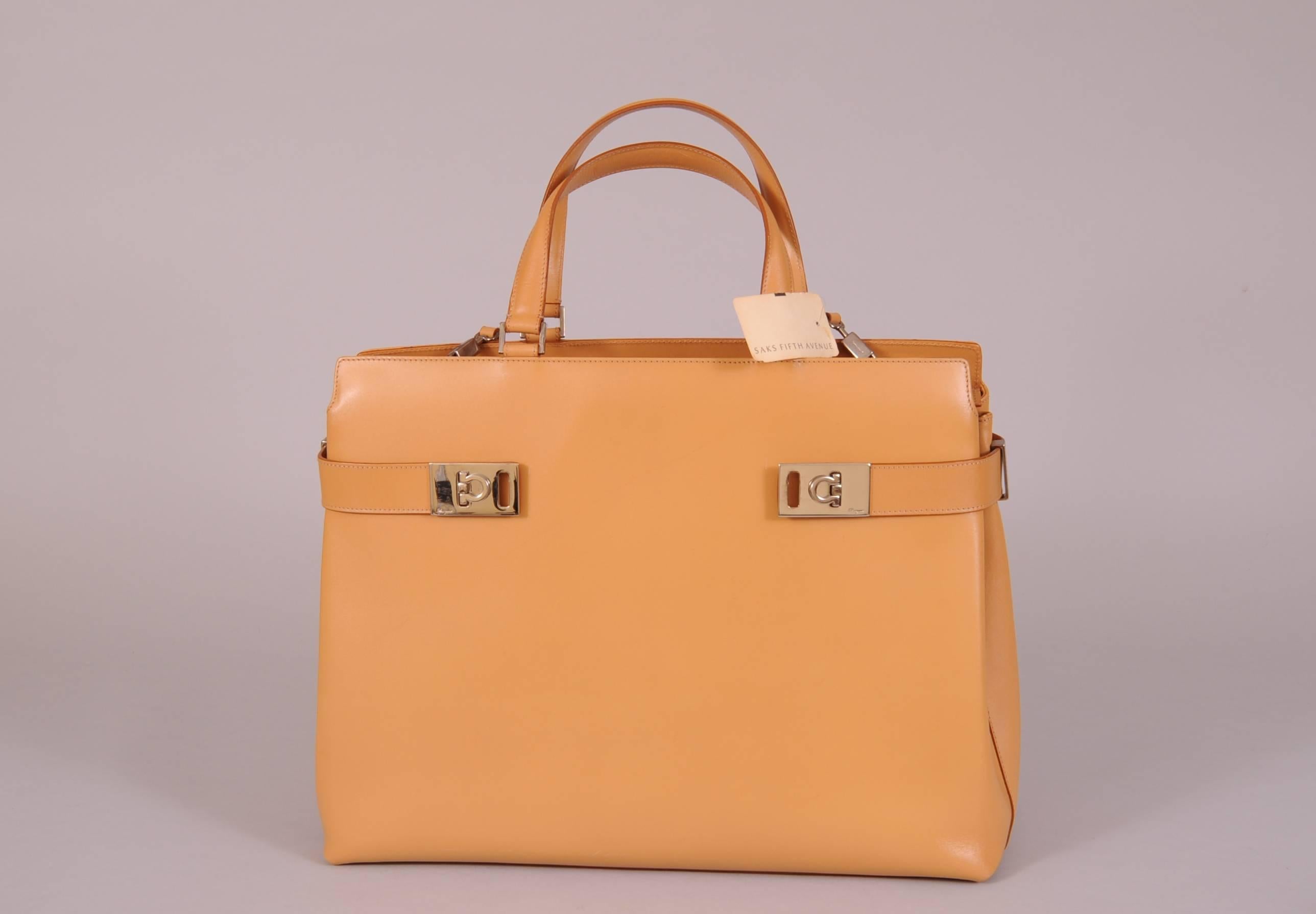 Natural colored leather and bright silver toned hardware create an elegant, never used day bag from Ferragamo. It still retains the original tag from Saks Fifth Avenue. The bag has an optional shoulder strap and it opens with a zipper at the top.