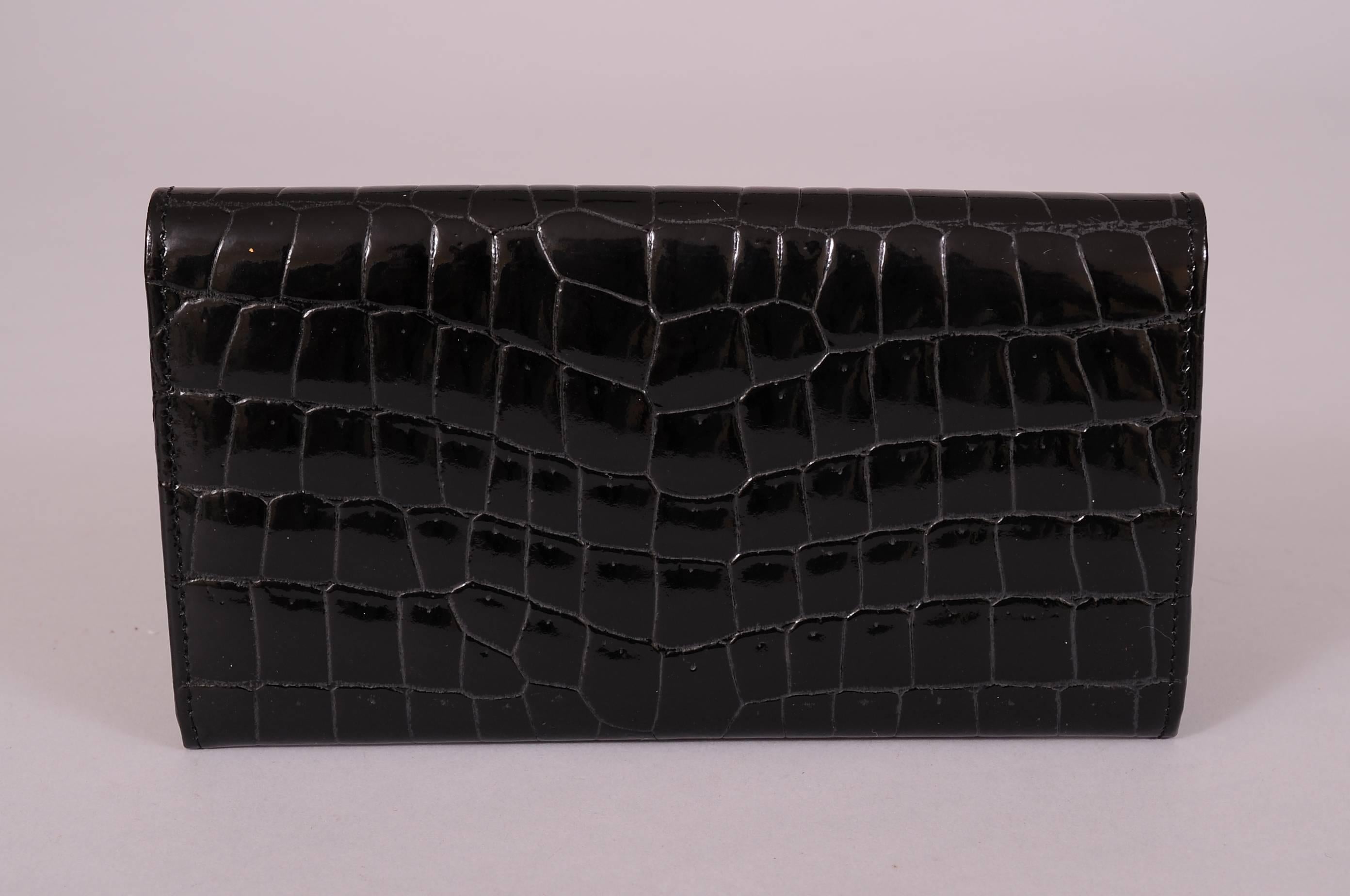 This 100+ year old French leather goods house has created a chic and functional black crocodile wallet with a snap closure. There are two large open pockets, one zippered section and three slip pockets inside. It has never been used and is in