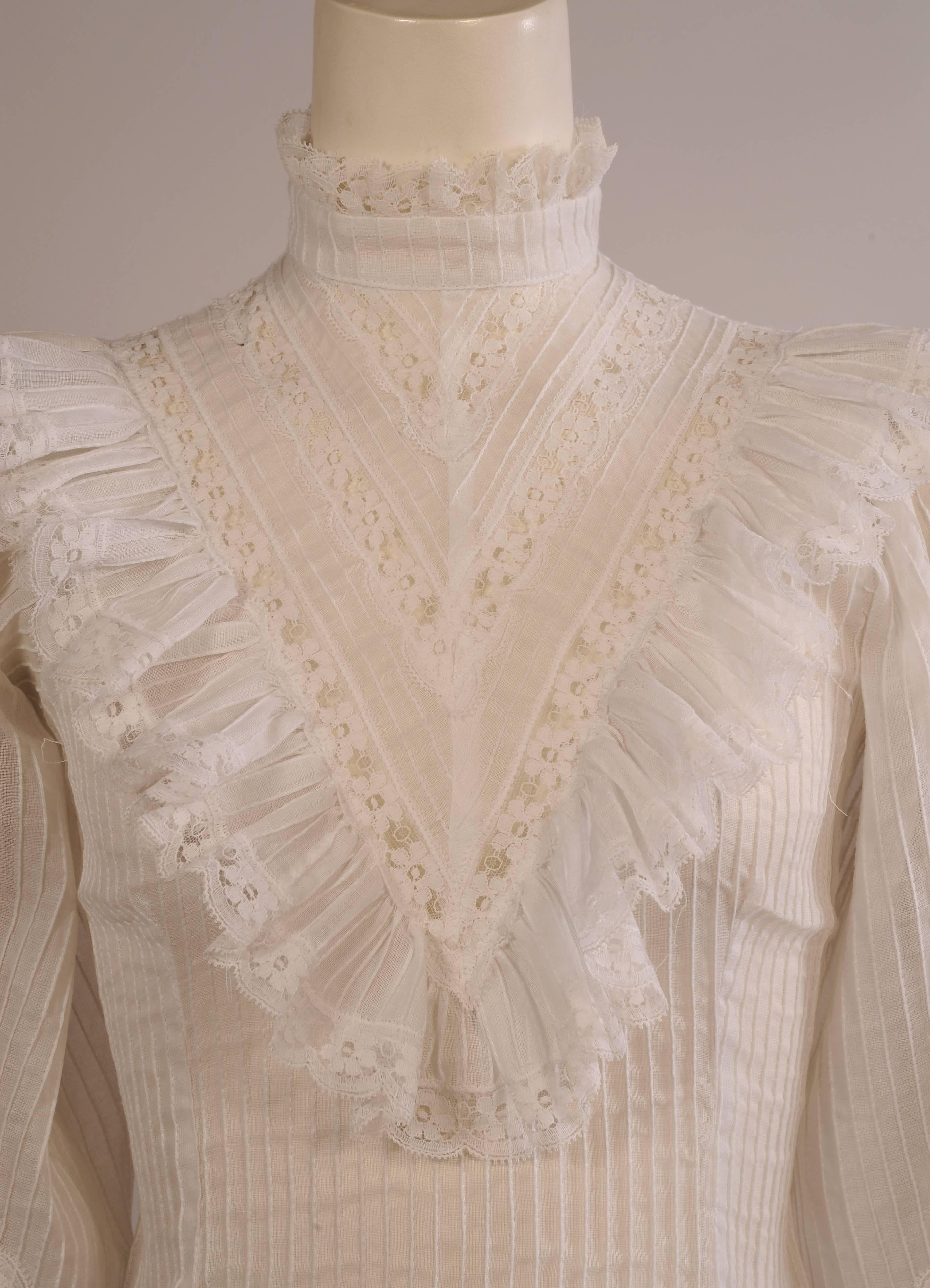 Inspired by the resurgence of Victorian clothing in the 1970's vintage clothing market this blouse is a very well done recreation. The lace trimmed high collar and ruffled yoke front are complimented by lace insertion in the full sleeves.
The fitted