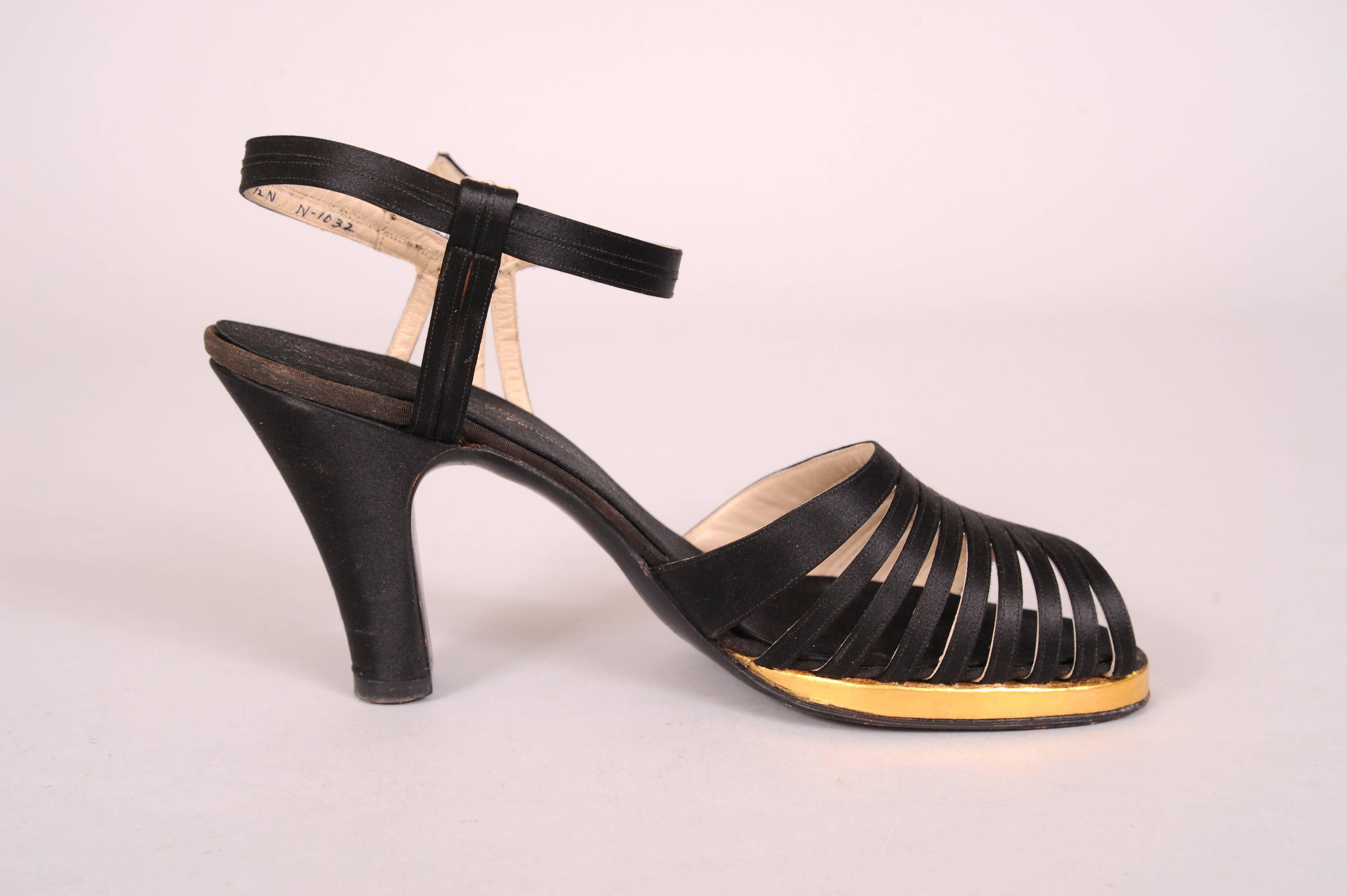 These lovely black silk evening shoes have nine leather backed silk straps, set on an angle, above a gold kid platform. The ankle strap has four silk straps below the buckle. Worn only once they are in excellent condition with only minor wear to the