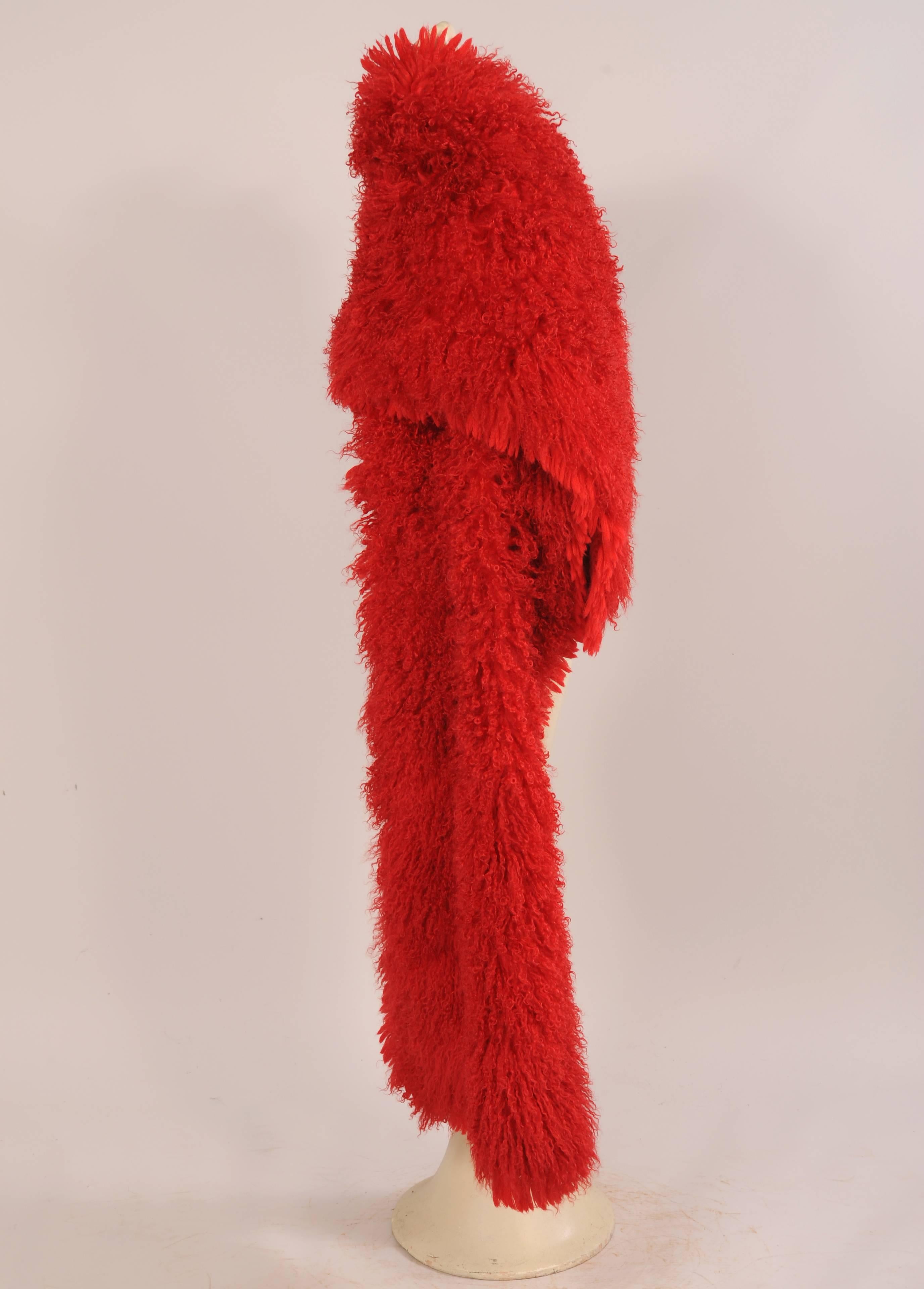 This luxurious red curly lamb stole is so eye catching! Almost three yards long it is a very dramatic and warm wrap. The fur has a matching red wool fringe on all four sides and it is lined with a matching red silk moire.
It is in excellent