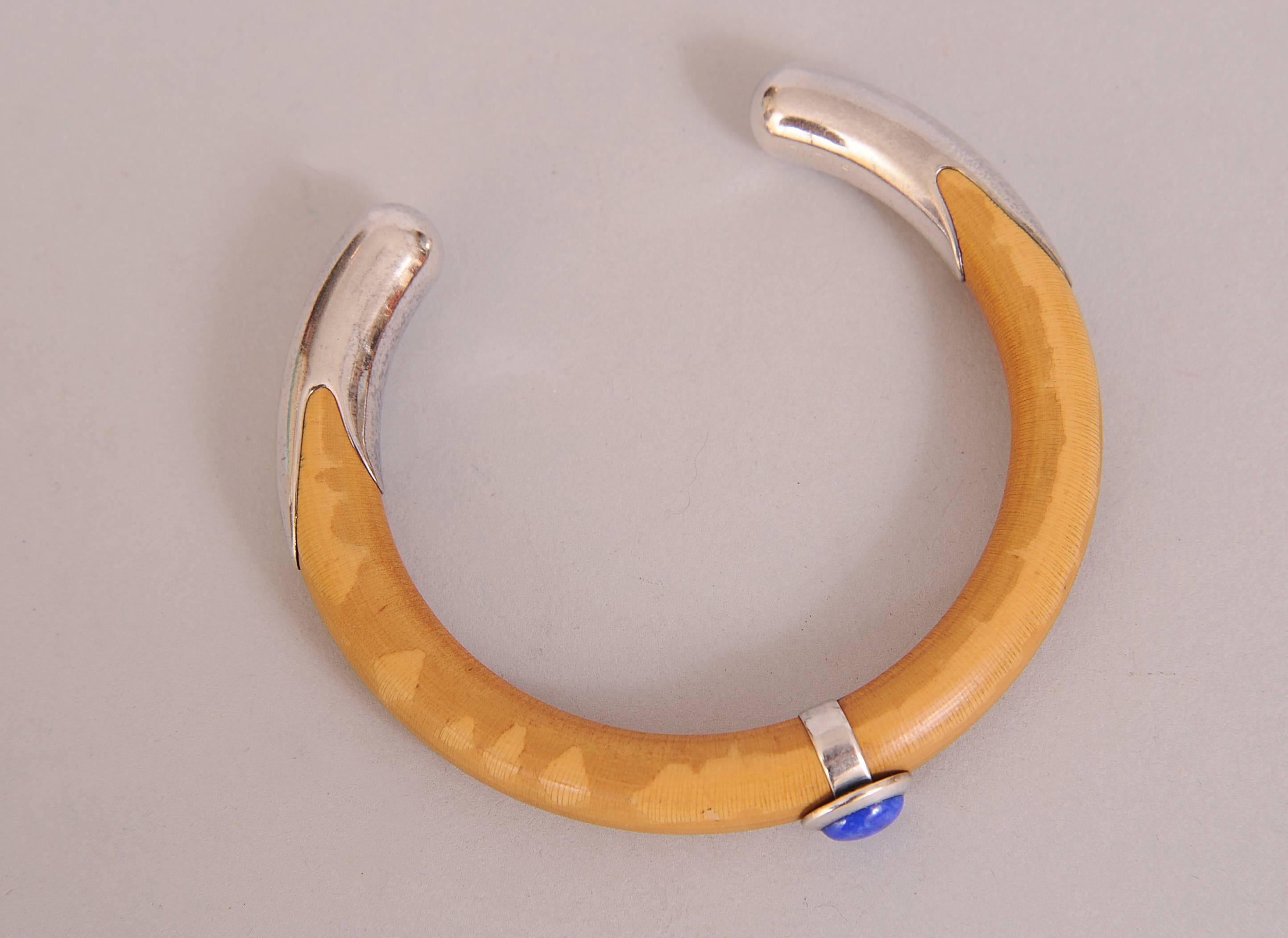 Bamboo is shaped to form a sleek and elegant cuff bracelet designed by Elsa Peretti. The center of the bracelet is wrapped with a sterling bad set with a beautiful piece of lapis lazuli. The ends of the cuff are capped with sterling silver. One side