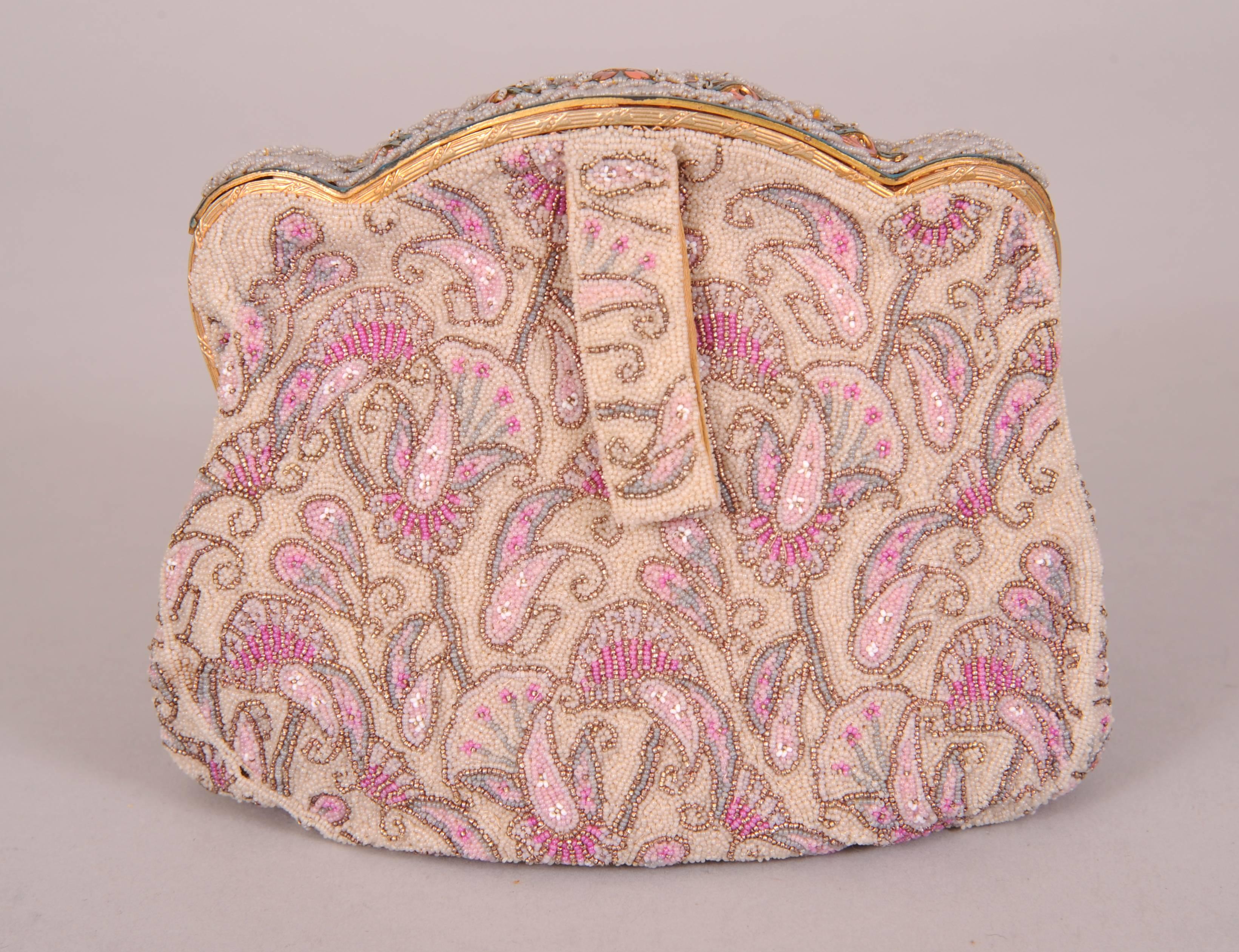 This beautiful beaded French evening bag has a pastel pink floral design, edged in silver beads , on an oyster colored beaded background. The caviar beads are very small and delicate, a size no longer used today.  The bag has a beaded frame with an