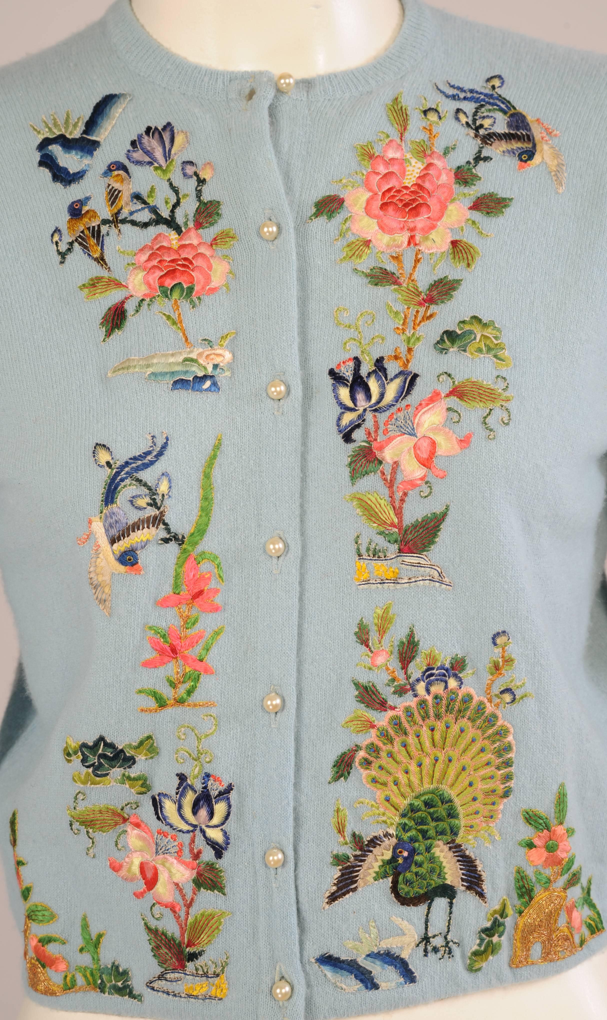 Pale blue cashmere is hand appliqued with exquisite colorful hand embroidered Chinese silk designs. There 
are flowers and vines, and birds in the trees as well as a peacock on the left front and the center back. All of this was cut from antique