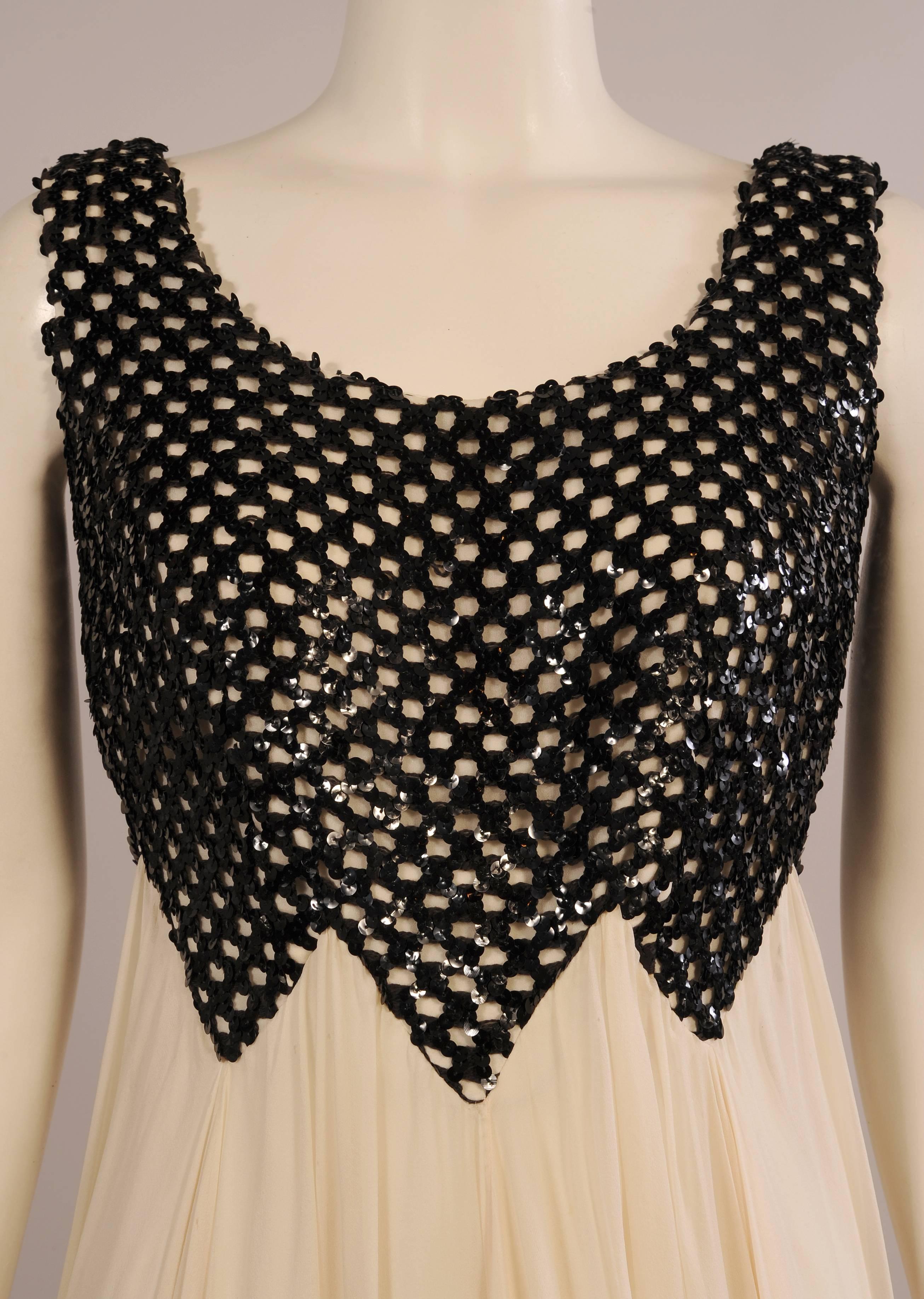 An ivory crepe top is covered with an unusual lattice work of black sequins. The pointed hem of the top ties in perfectly with the gathered sections of the ivory silk chiffon skirt. This floating layer of chiffon has a matching ivory crepe