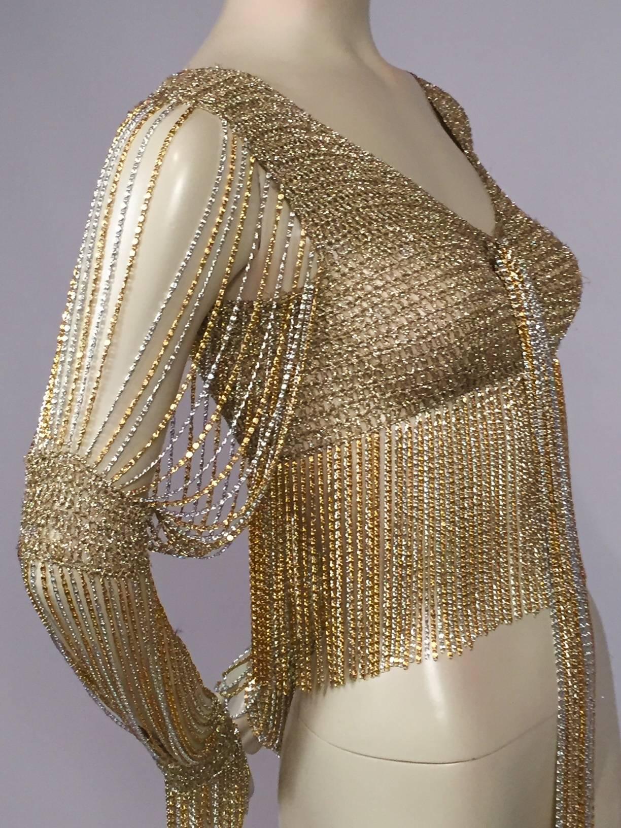 This is not your Grandmother's crocheted cardigan! Loris Azzaro has combined silver and gold lurex yarn for the body of this piece as well as the two bands on each sleeve. The sleeves have three sections of silver and gold chain in between the the