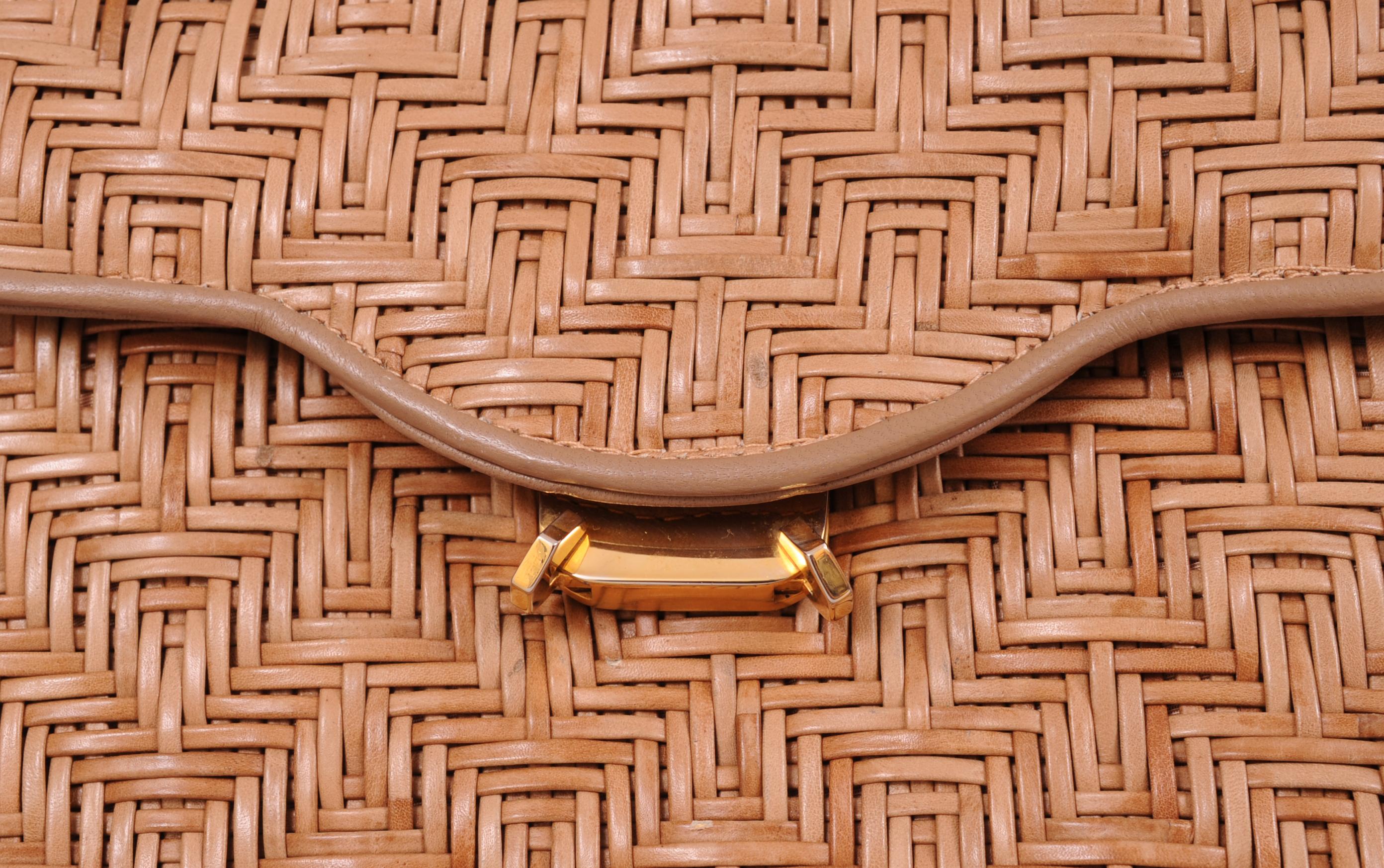 Cocoa brown leather strips are woven in a basket pattern and trimmed with matching leather. The same leather is used for the lining of the flap. There is a chic wooden handle with gold toned hardware and a double row of gold toned metal 