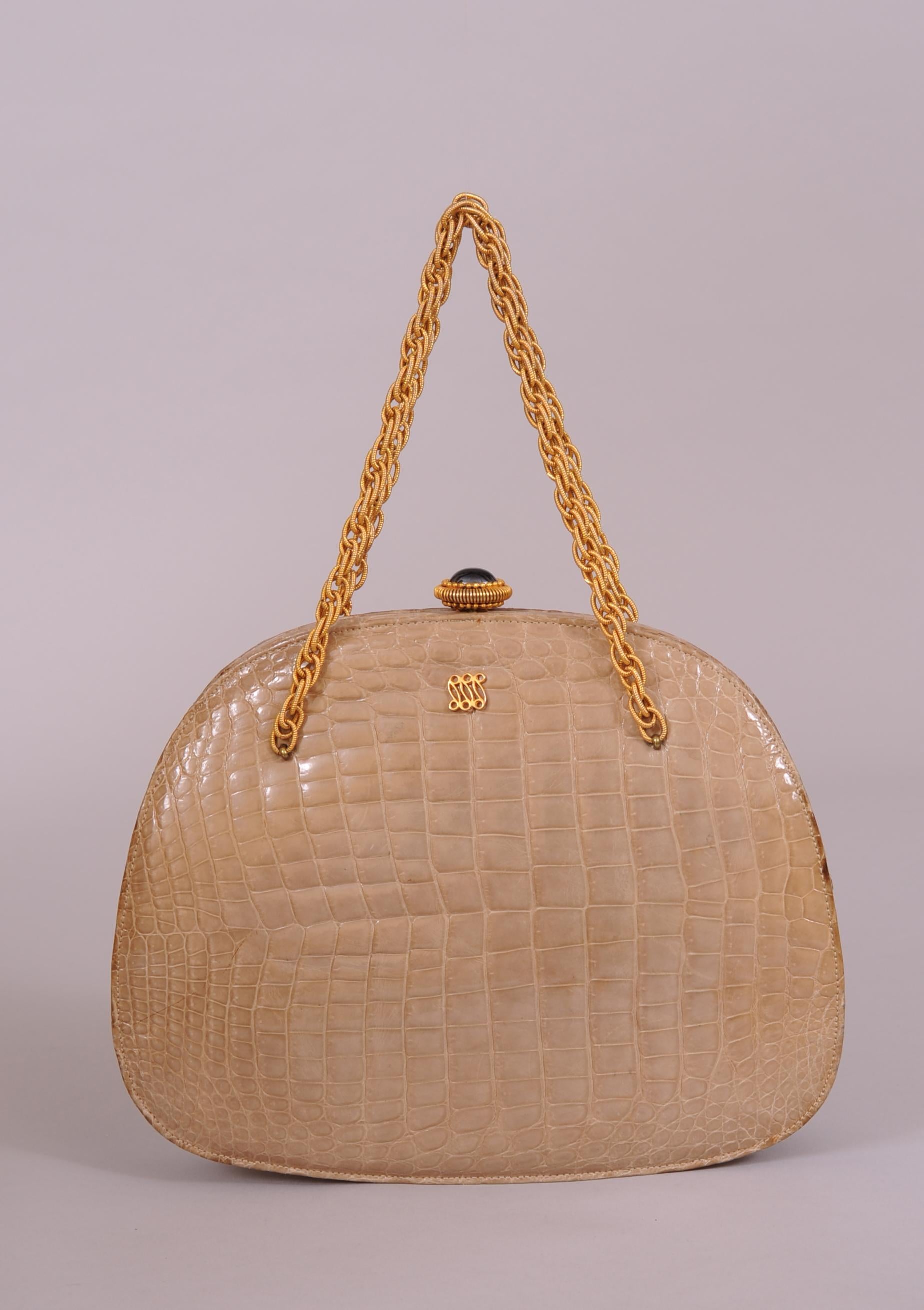 A great pale beige crocodile bag from Lucille de Paris is embellished with a large cabochon clasp and gold toned chain straps. The interior is natural leather with the Lucille name and logo and Made in USA stamped in gold. There is one zippered