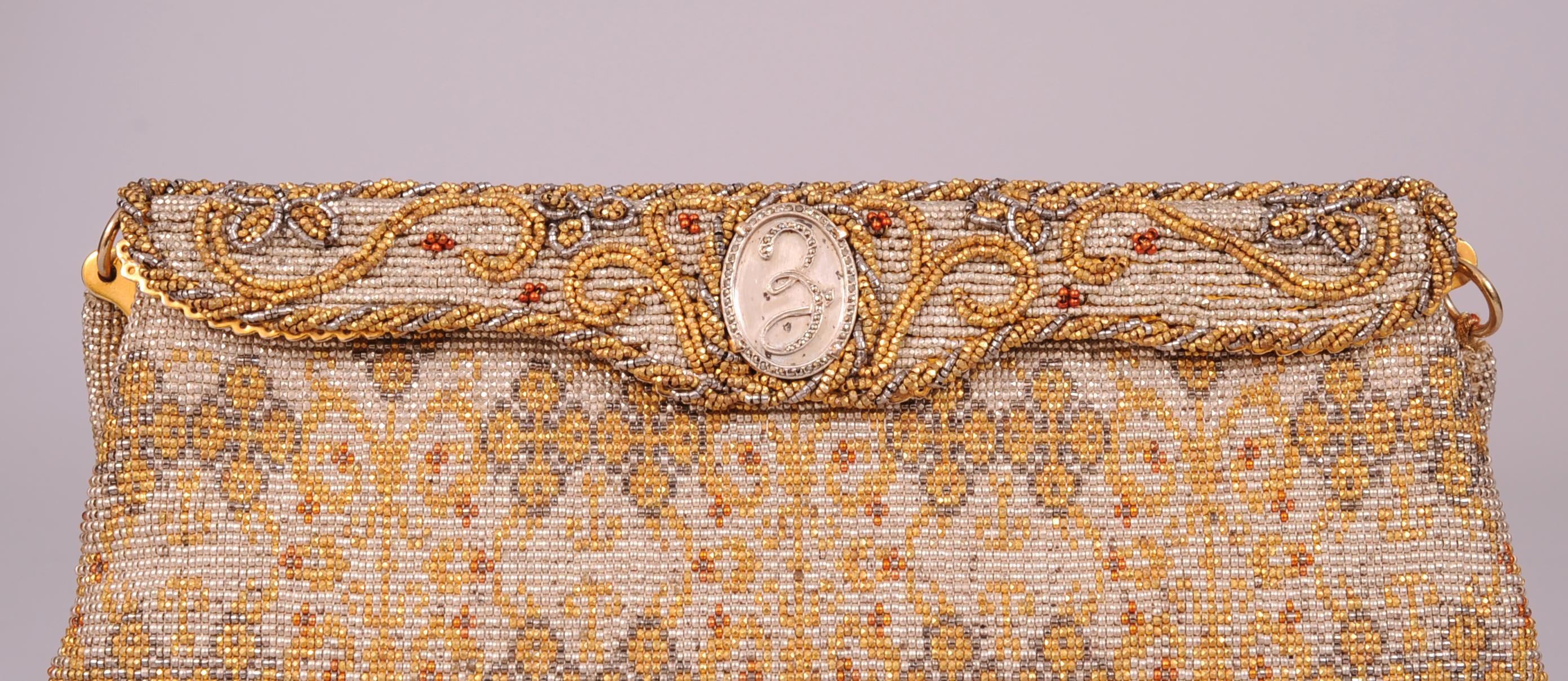 Beautifully hand beaded in France this Morabito bag has a platinum beaded background with designs worked in gold, silver and a touch of red. The frame is completely beaded with a meandering flower and vine design applied to the beaded background