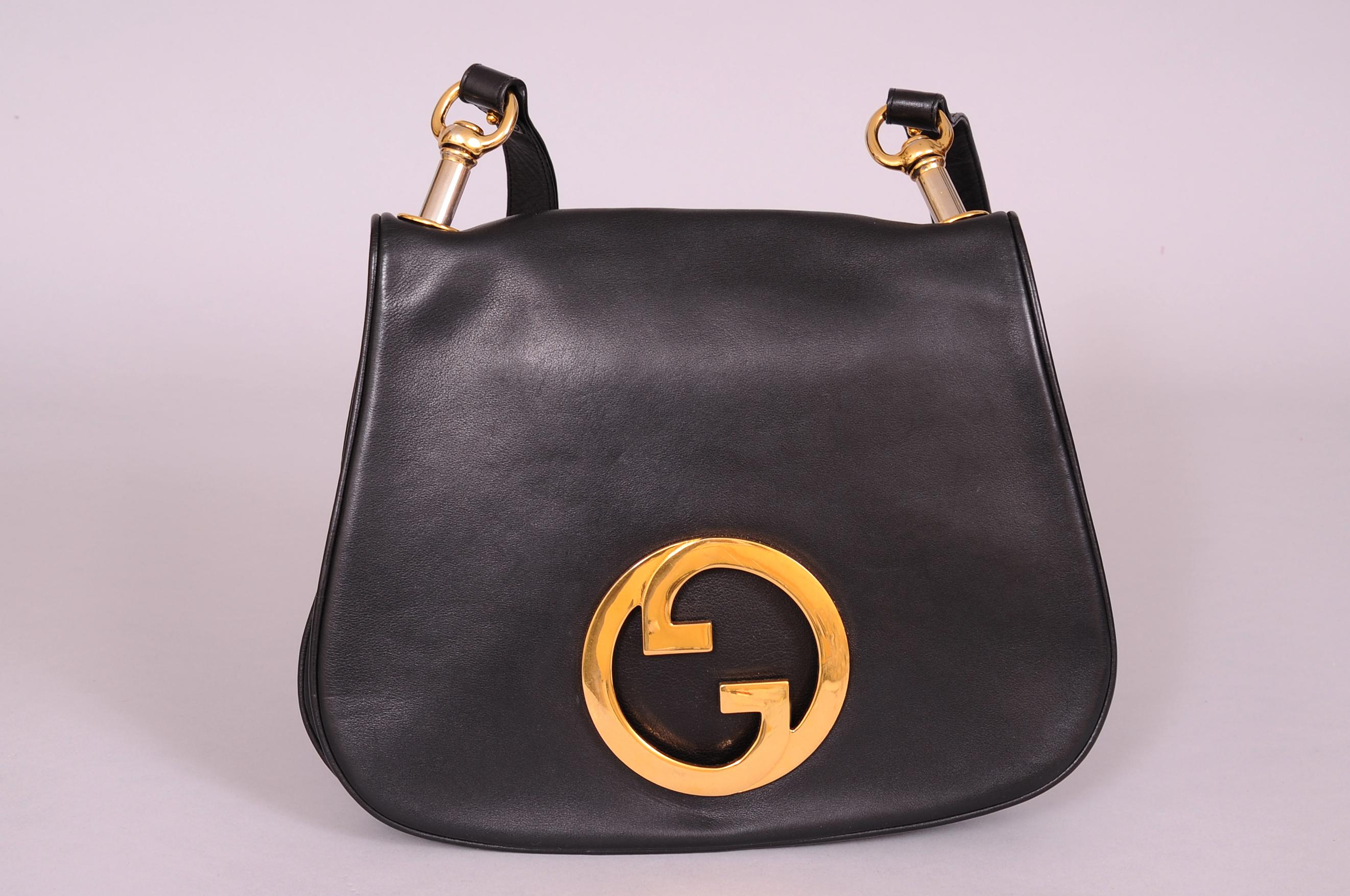 The iconic Gucci gold toned intertwined double G logo is front and center on this supple black leather Blondie bag from the 1970's.  The soft black leather bag has a black leather shoulder strap with a gold toned buckle to adjust the length. Two
