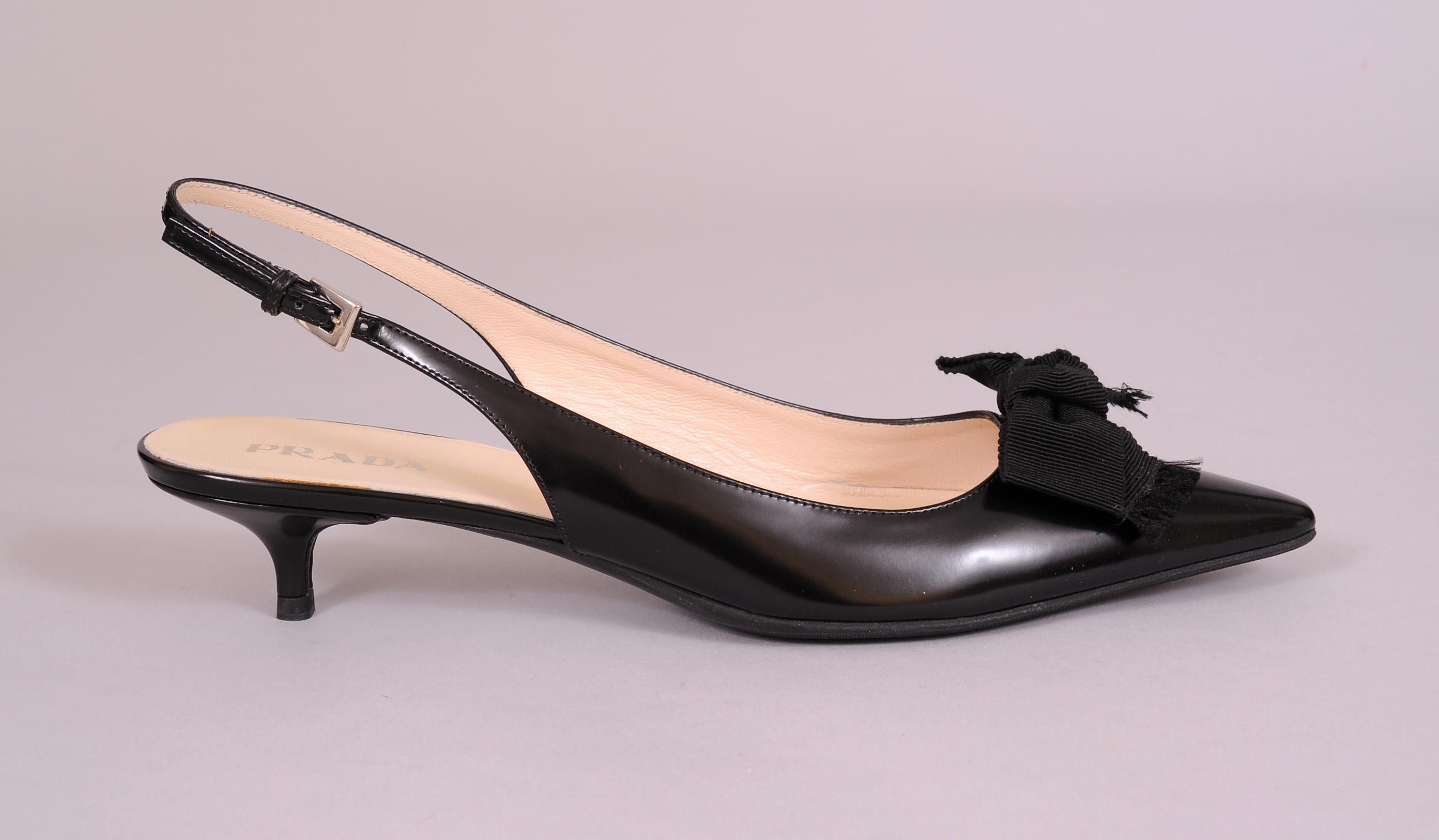 Black calfskin is accented with black faille bows on these sling back kitten heeled Prada shoes. They have never been worn, still in the original box they are in excellent condition. They are marked a size 40 1/2 and they have the original non slip