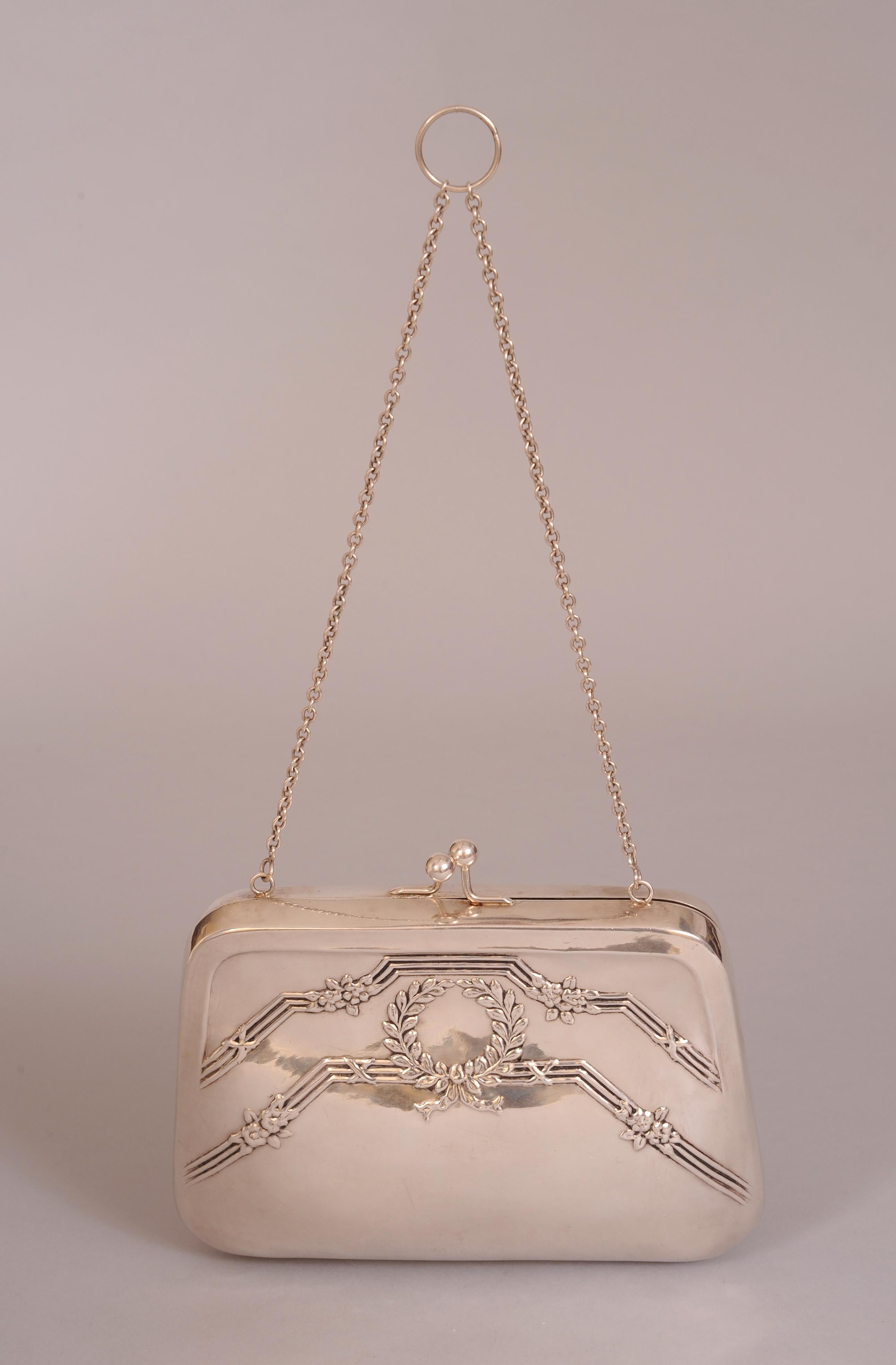 This roomy silver bag from Roberta di Camerino is large enough to hold a phone and all of the rest  of your necessities for an evening on the town.  It has a kiss lock closure, a chain strap and a burgundy satin interior with a slip pocket. Both