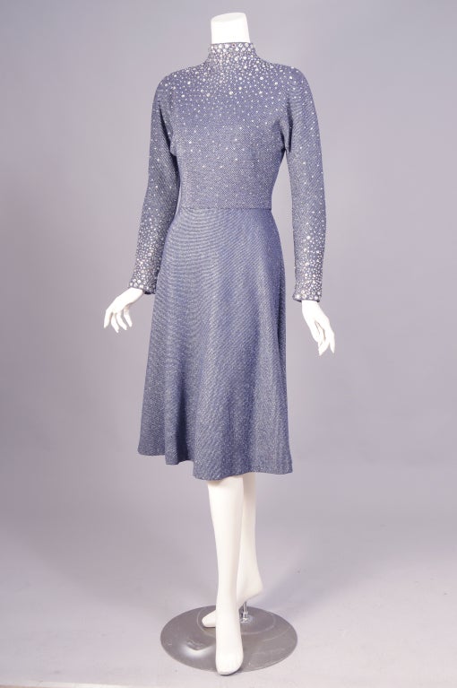 Navy blue and silver wool is embellished with hundreds of prong set rhinestones of varying sizes in this great 1970's dress from Pauline Trigere. The dress has a mock turtleneck, long sleeves, a fitted wasit and a dance skirt with one large