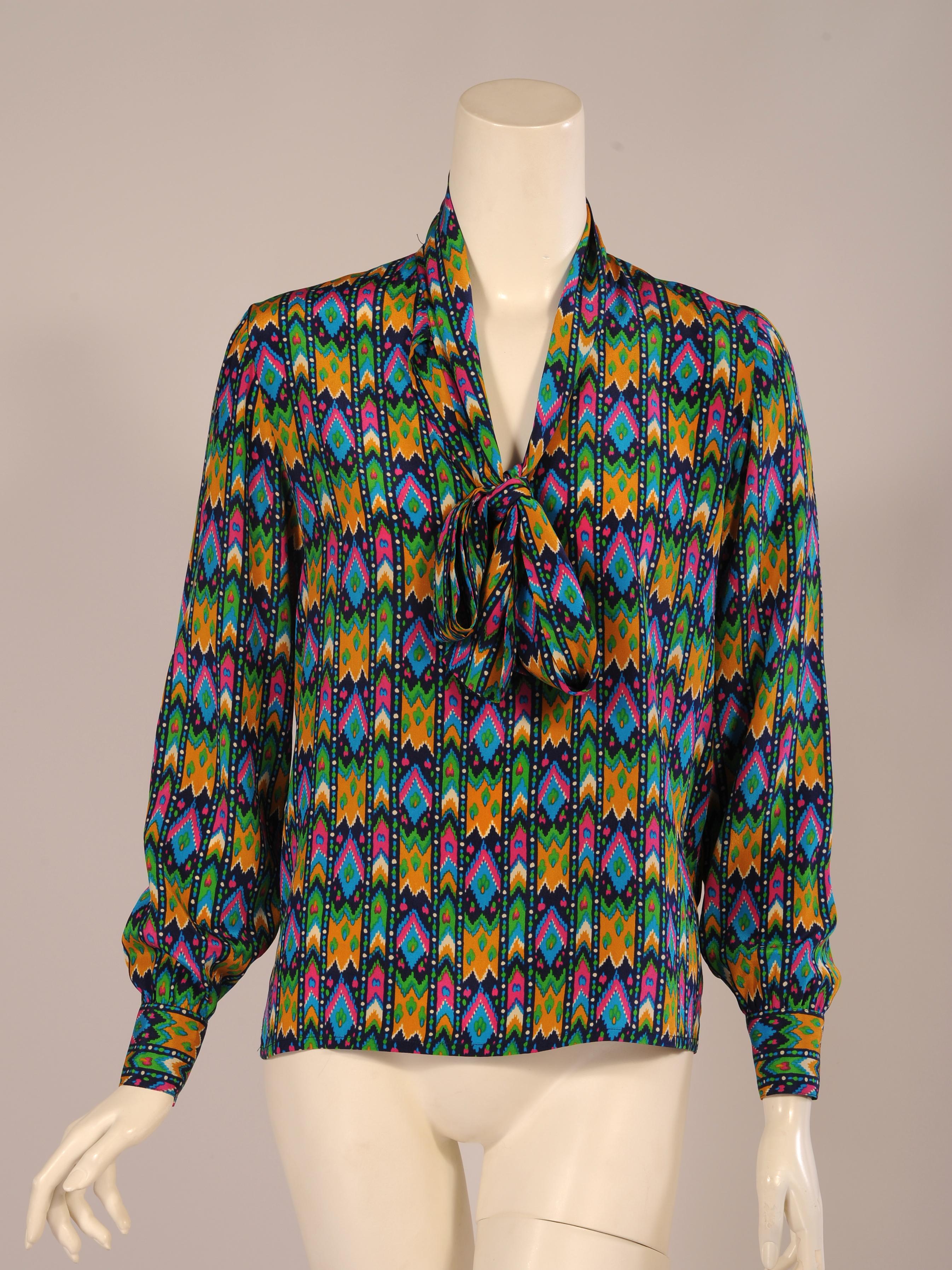 This fabulous silk print blouse from the YSL Rive Gauche line just slips on over your head. The collar becomes a tie or pussy cat bow. The long sleeves have button cuffs. The simplicity of the blouse design allows the pattern of the silk to be the