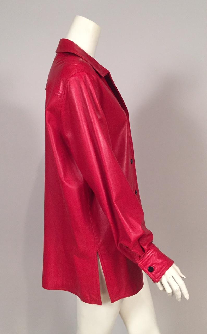 Soft and supple true red lambskin is perfect for this oversized leather shirt jacket from Bill Blass. It has one breast pocket, black buttons at the center front and cuffs and a split hem on either side. It is fully lined in matching red silk and it