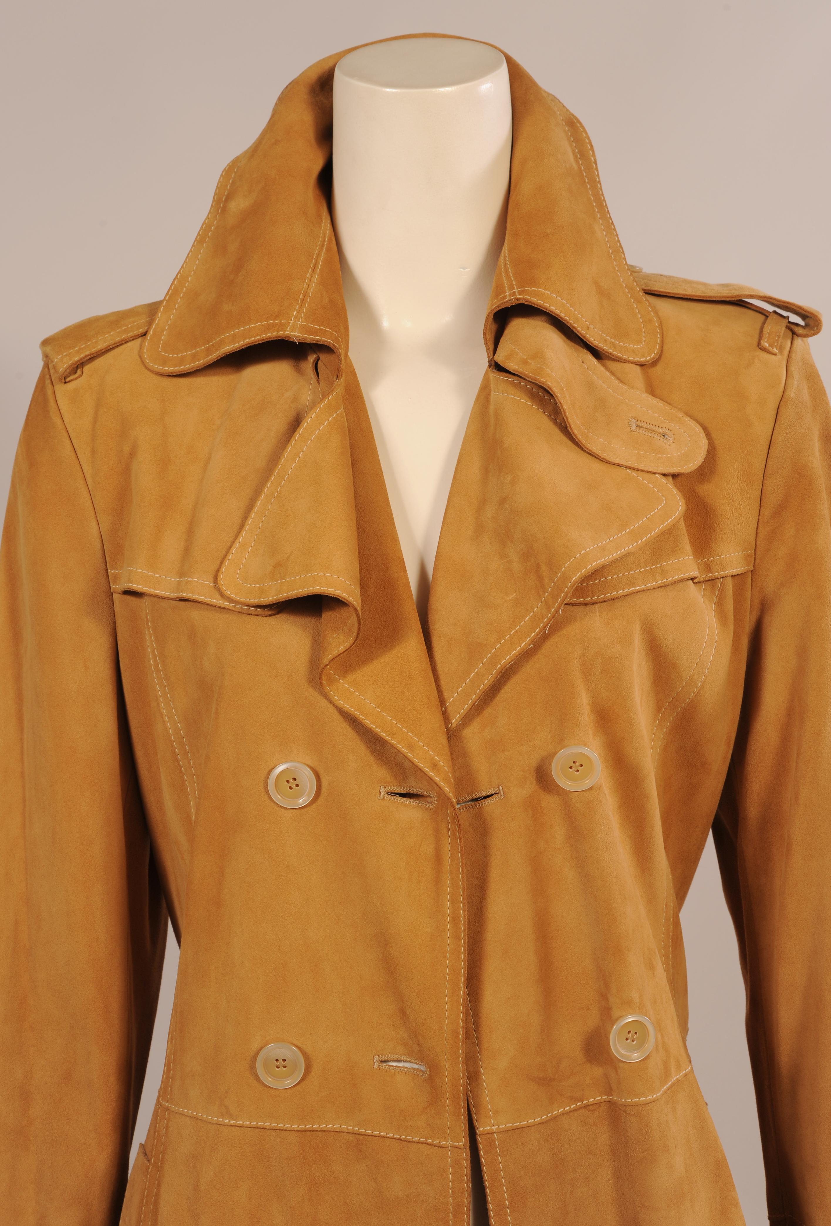 This rich caramel suede coat is designed in the classic trench coat style. Shoulder epaulets, a front yoke and a tie belt are all emblematic of the style. It is double breasted and there are two pockets. The coat is in excellent