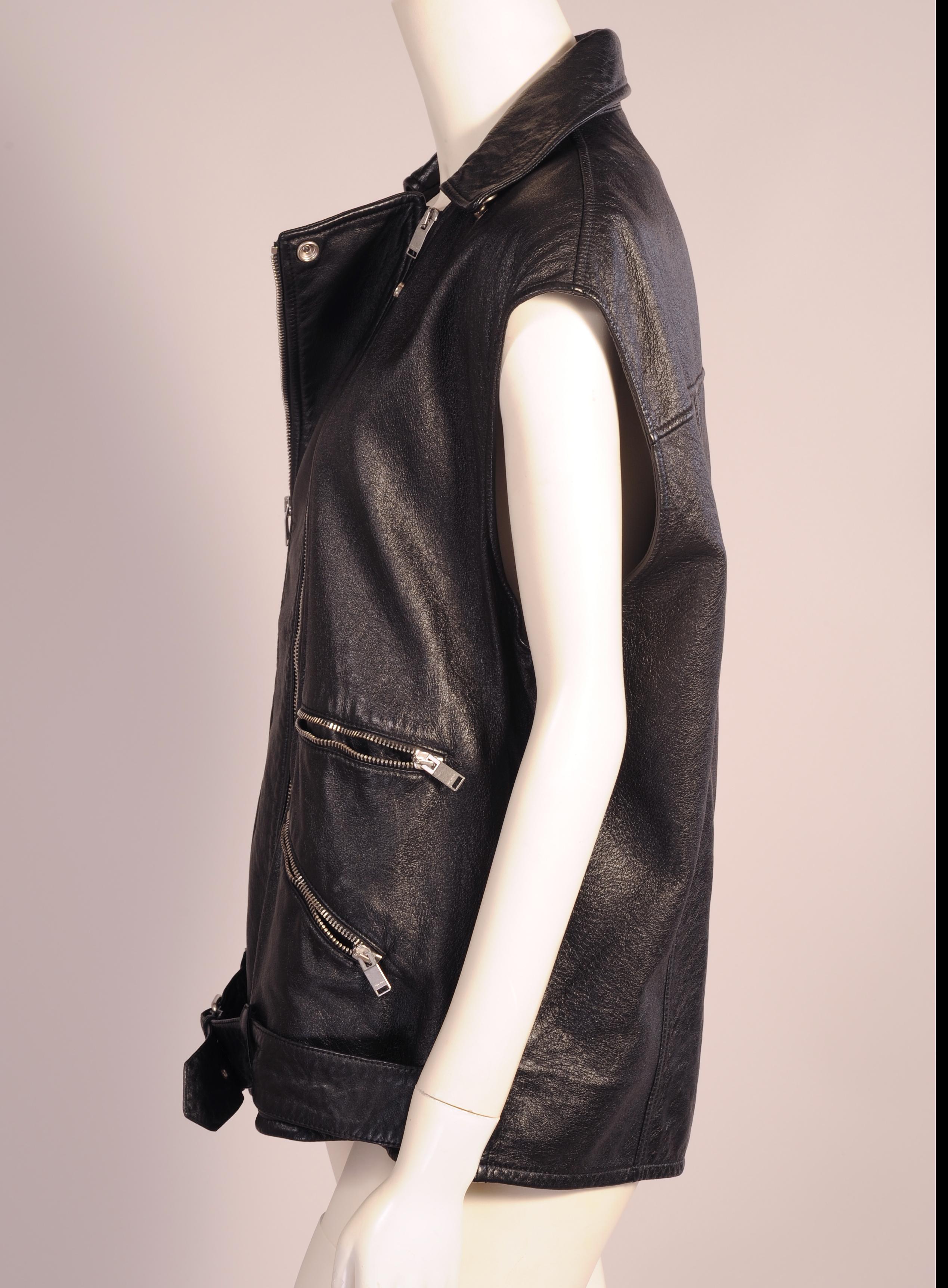 A stylish version of the classic biker jacket this sleeveless jacket is made from black leather with a double zipper opening, two zippered pockets on each side, and a half belt with buckle. It is in excellent condition and marked a French size