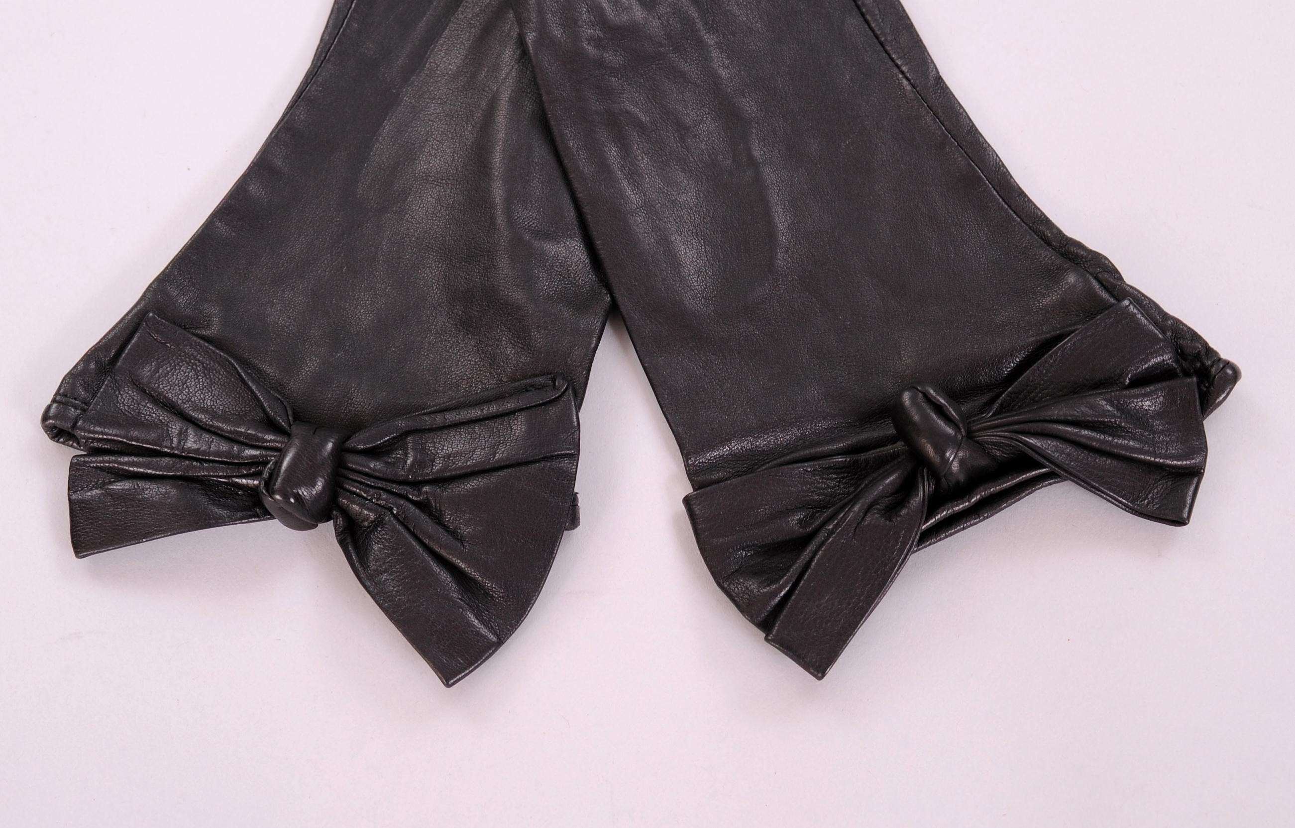 These butter soft black leather gloves designed by Carlos Falchi have a wonderful leather bow and knot at the wrist. They are lined in black silk and marked a size 7. Never worn, they are in pristine condition. 