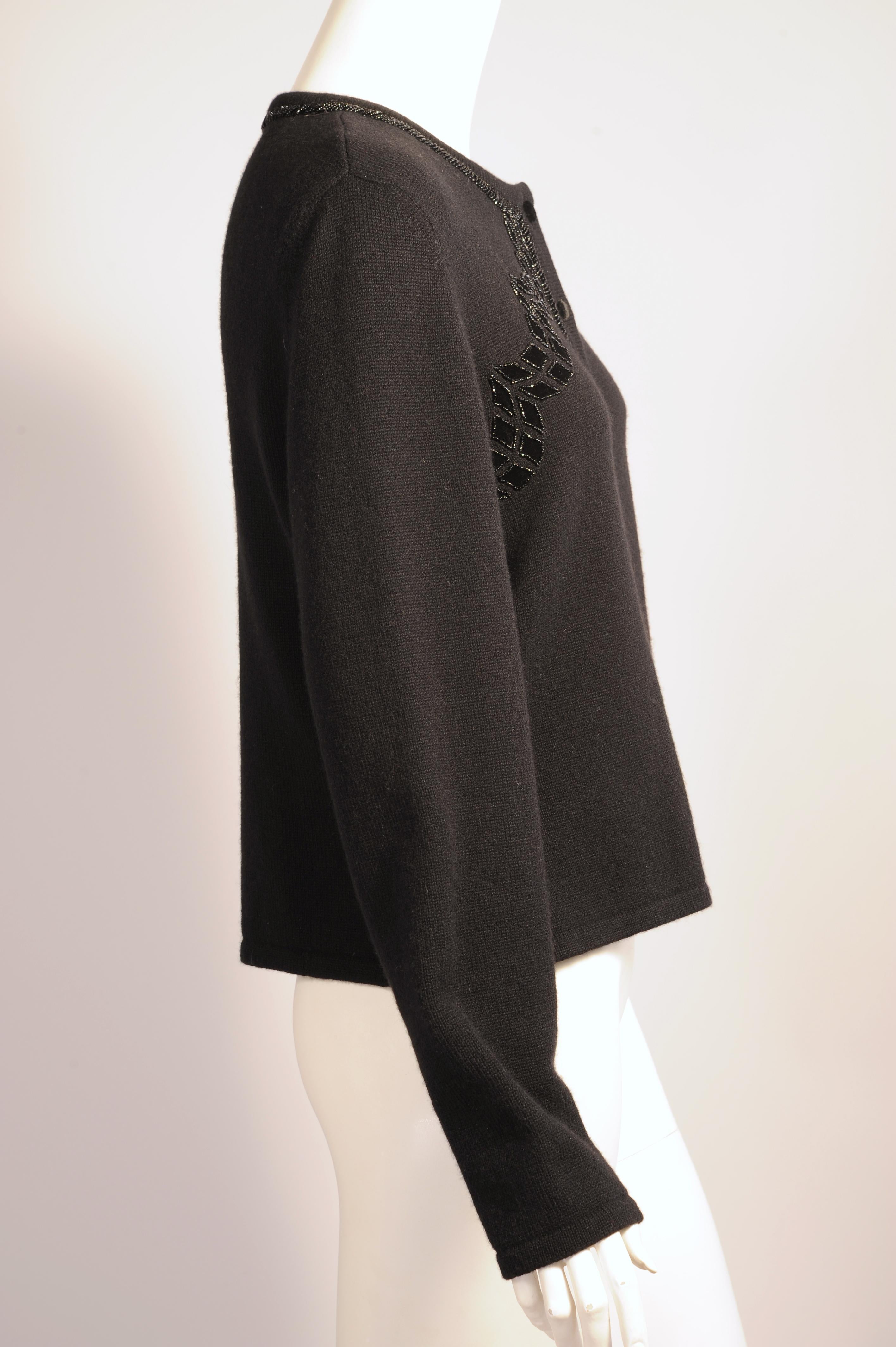 Italian cashmere in a classic cardigan style is elevated to evening wear by Carolina Herrera. The neckline and front opening are edged with diagonal rows of black caviar beads surrounding the black velvet buttons. There is a scalloped pattern of