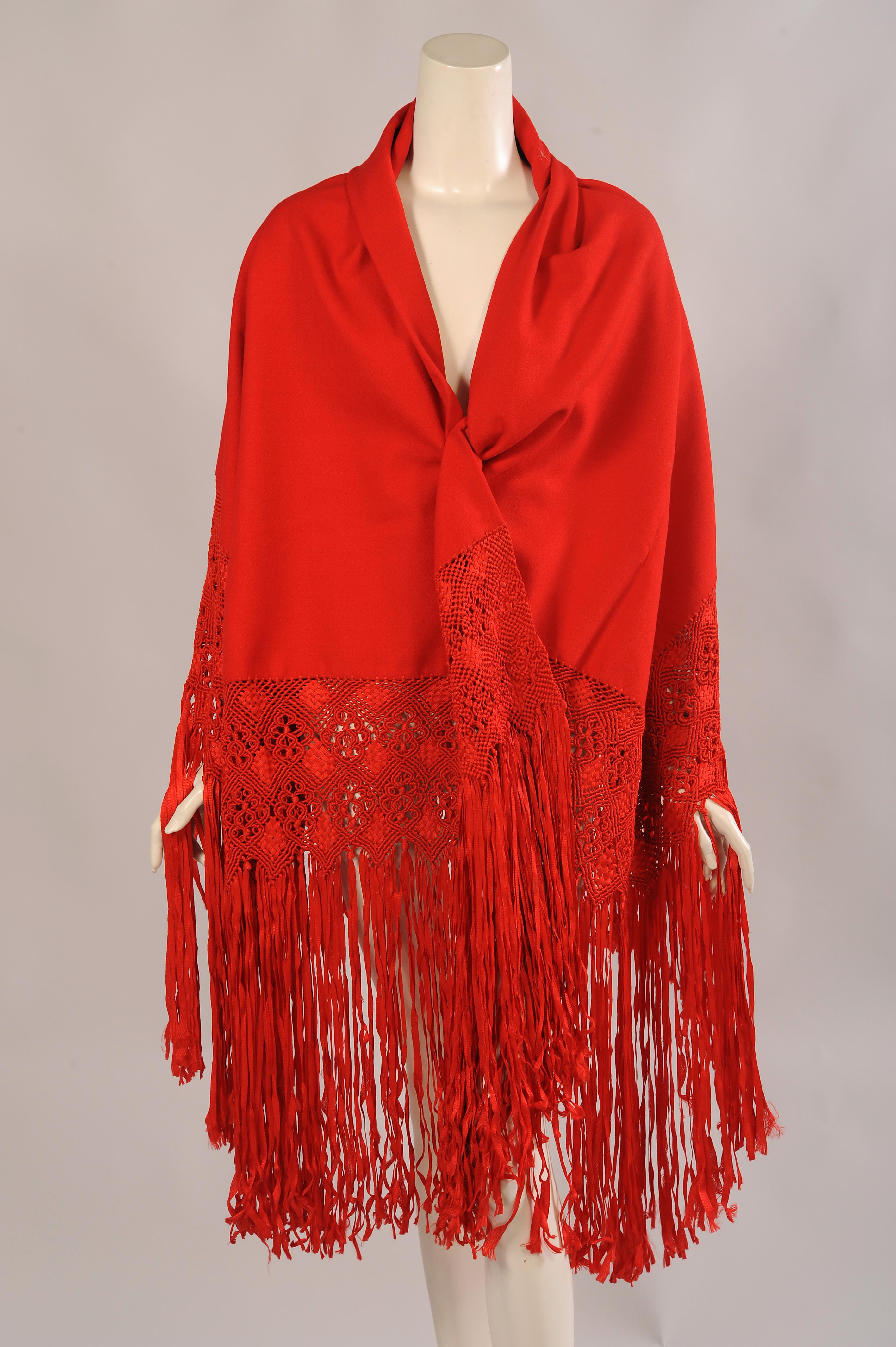 This shawl is so beautiful! A large square of red wool crepe is folded in half for extra body and warmth. It is then lavishly trimmed with red silk macrame work and fringe. All of this is done by hand and it is quire spectacular. There are braided,
