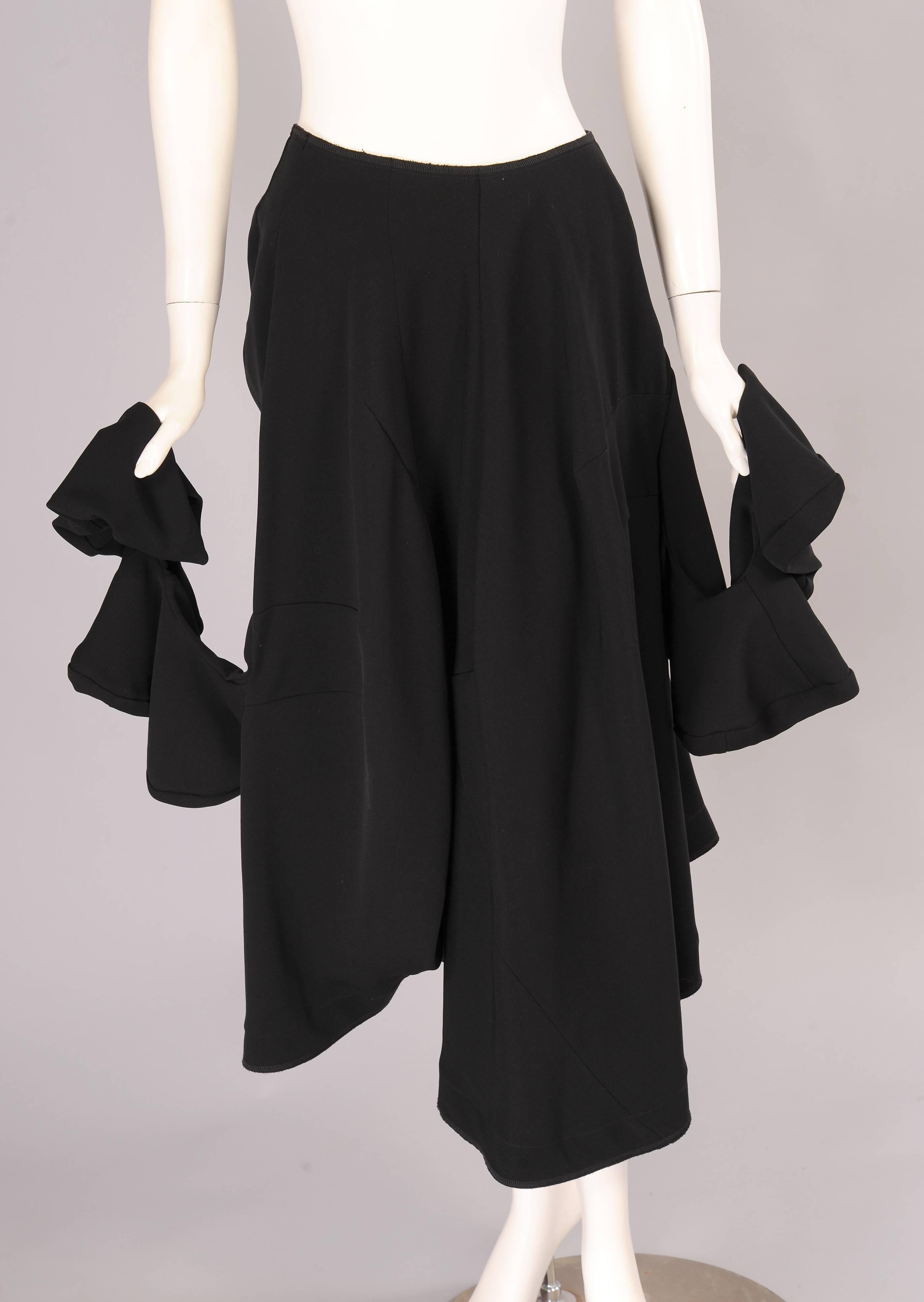 Sorprendente y divertida, esta inusual falda de Comme des Garcons tiene mangas retorcidas a cada lado que añaden interés y más que un poco de capricho. La falda está confeccionada sin cinturilla. Hay una cremallera en la espalda y una gran cantidad