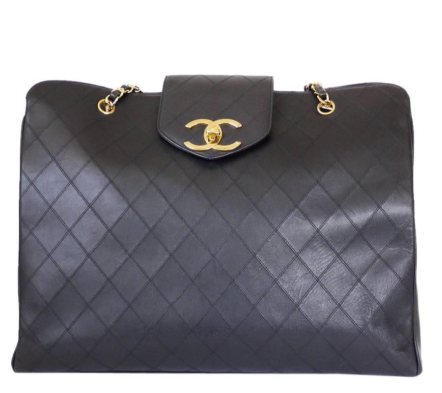 CHANEL black lamb skin flat quilt overnight bag, weekender shoulder bag in excellent used condition. This overnight bag offers a spacious interior and a large CC turn lock closure. It is ideal as a shopping bag or weekend bag. Many celebrities are