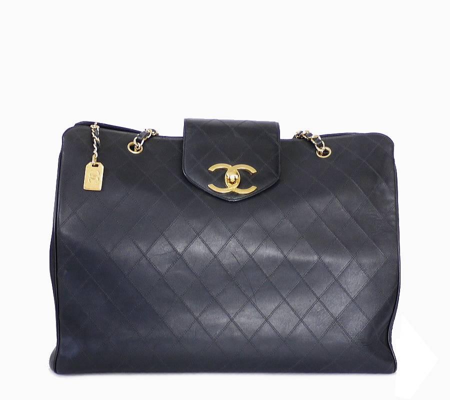 CHANEL black lamb skin flat quilt weekender, weekender shoulder bag in excellent used condition. This overnight bag offers a spacious interior and a large CC turn lock closure. It is ideal as a shopping bag or weekend bag. Many celebrities are